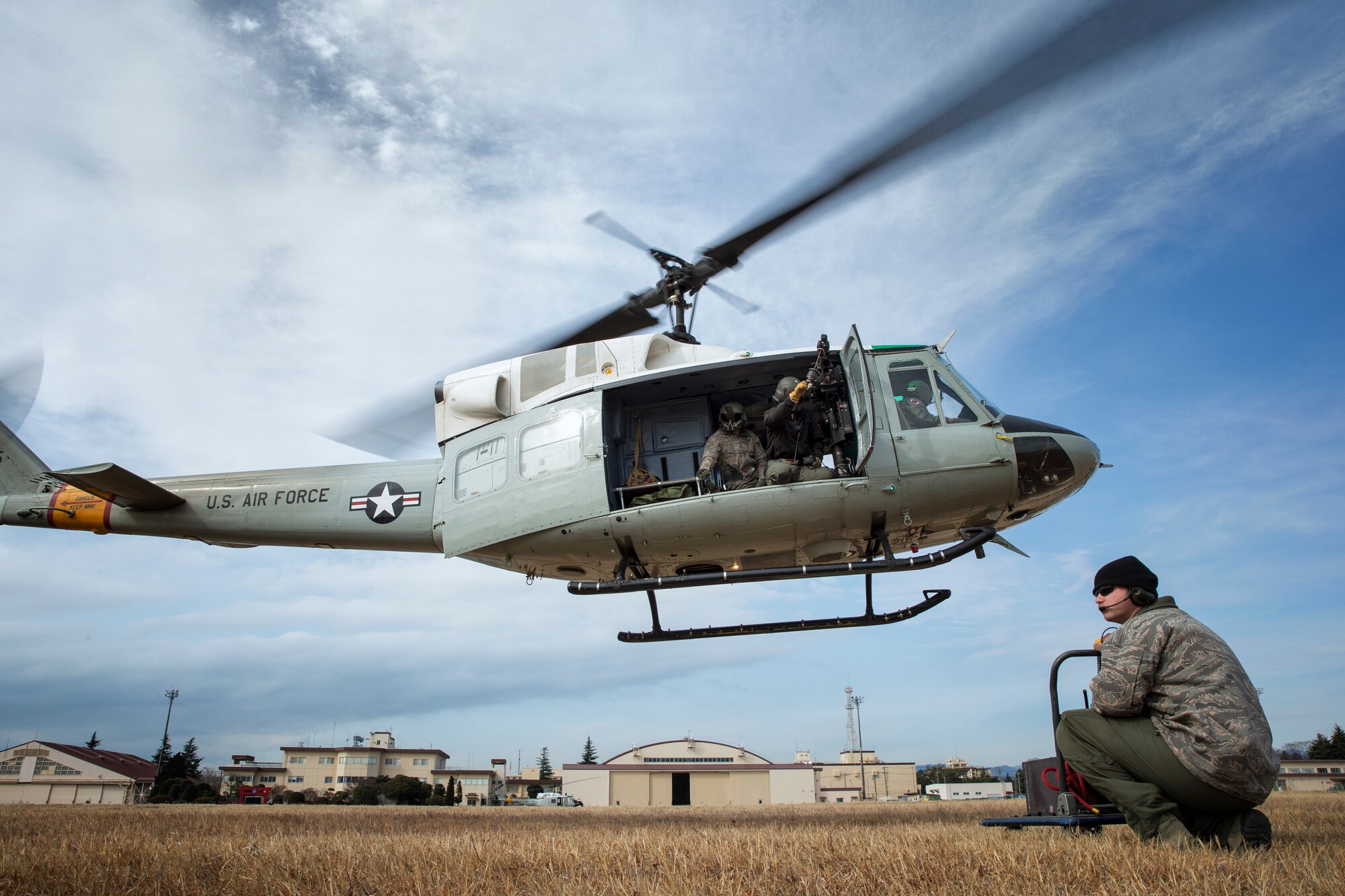 Tech. Sgt. Christopher Rector, 459th Airlift Squadron flight engineer, communicates with UH-1 crews from the ground at Yokota Air Base, Japan, Feb. 22, 2016. The 459 AS recently improved their search and rescue capabilities by outfitting two UH-1N Hueys with new rescue hoists. Previously, without the hoist, conducting rescues in small, tight areas wasn’t feasible. Now, 459 AS aircrew can conduct any type of search and rescue scenario throughout the Kanto Plains. (U.S. Air Force photo by Osakabe Yasuo/Released) 