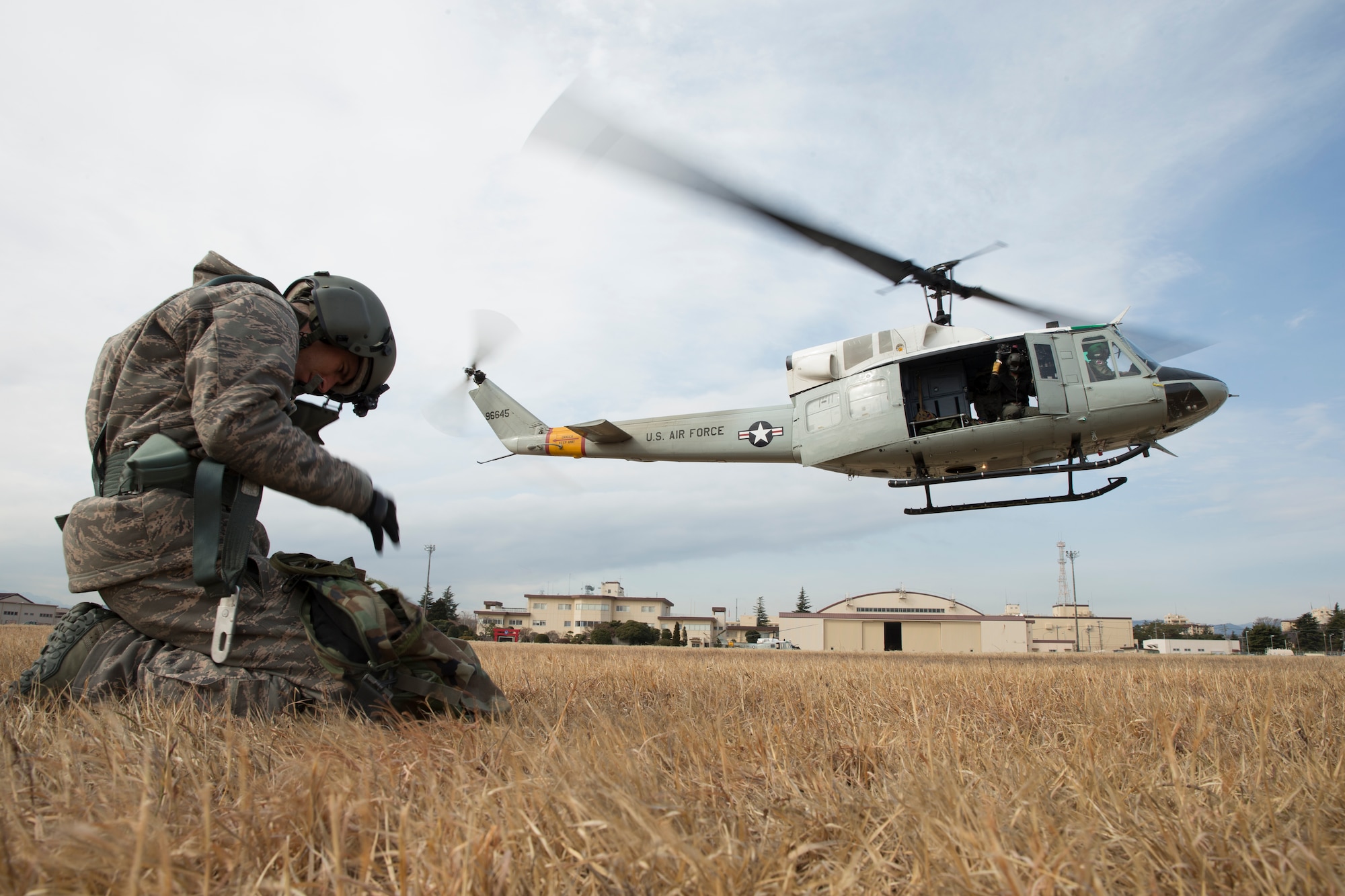Staff Sgt. Nicholas Poe, 459th Airlift Squadron fight engineer, waits for a UH-1 Huey to land during hoist training at Yokota Air Base, Japan, Feb. 22, 2016. The 459 AS recently improved their search and rescue capabilities by outfitting two UH-1N Hueys with new rescue hoists. Previously, without the hoist, conducting rescues in small, tight areas wasn’t feasible. Now, 459 AS aircrew can conduct any type of search and rescue scenario throughout the Kanto Plains. (U.S. Air Force photo by Osakabe Yasuo/Released)
