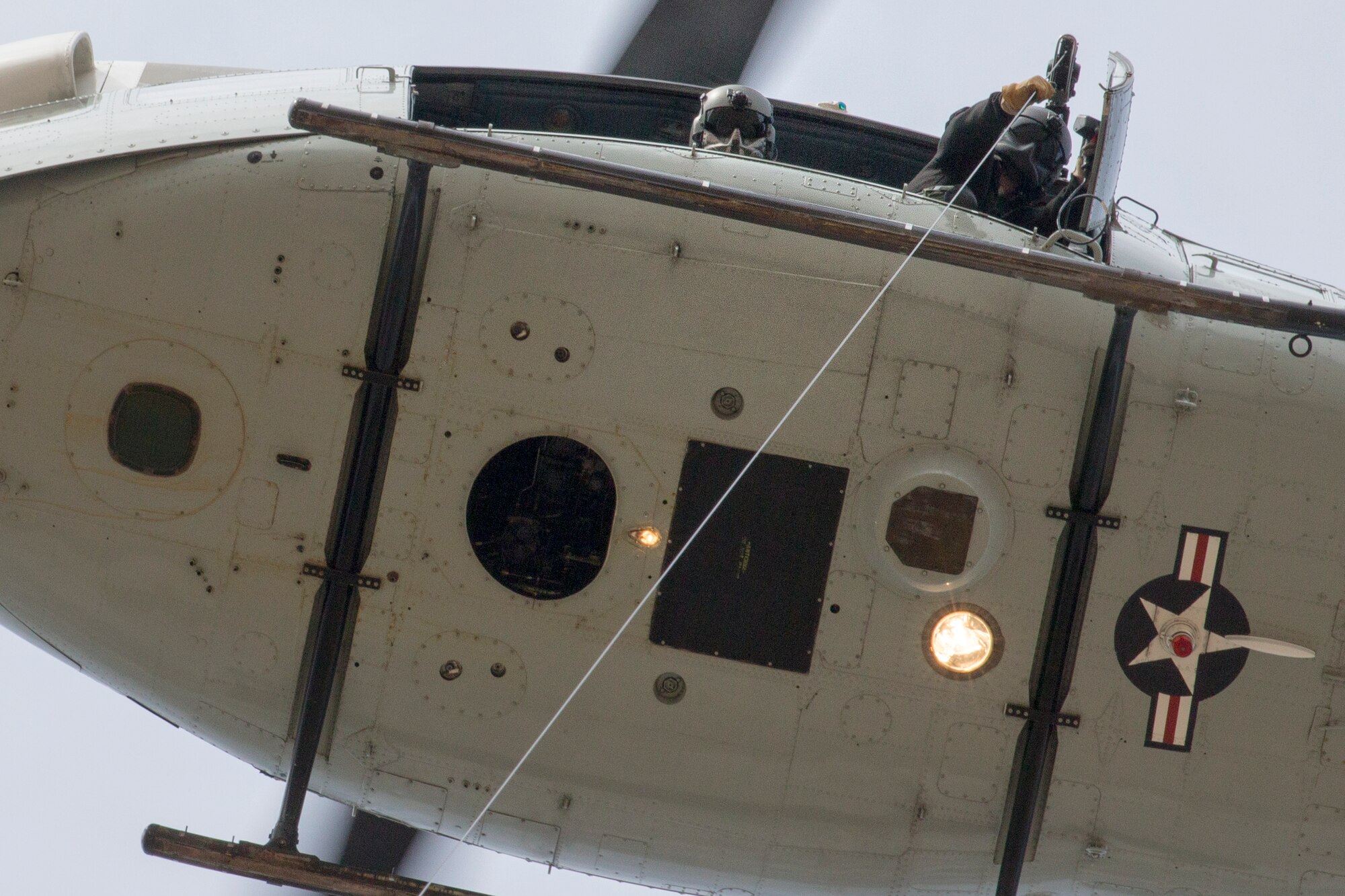 (Left to right) Tech. Sgt. Michael Wright, 459th Airlift Squadron flight engineer, and Tech. Sgt. Christopher Pound, 36th Rescue Squadron special missions aviator evaluator, perform hoist training at Yokota Air Base, Japan, Feb. 22, 2016.  The 459 AS recently improved their search and rescue capabilities by outfitting two UH-1N Hueys with new rescue hoists.  (U.S. Air Force photo by Osakabe Yasuo/Released)