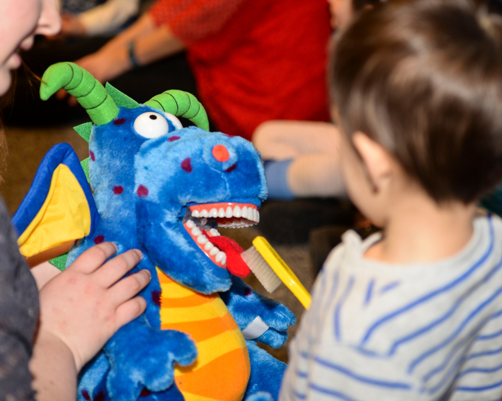 A child from Dakota Elementary brushes the teeth and tongue of a stuffed dragon at Minot Air Force Base, N.D., Feb. 18, 2016. The dragon was used during the dental health presentation given by 5th Medical Operations Squadron members to educate kids on dental hygiene practices during Children’s Dental Health Month. (U.S. Air Force photo/Airman 1st Class J.T. Armstrong)
