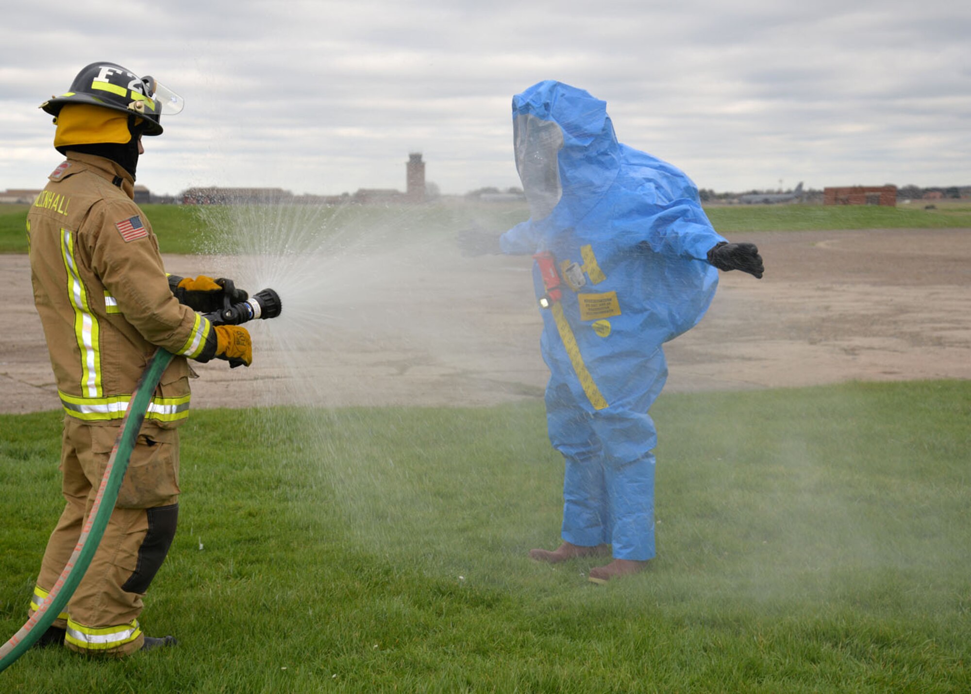 U.S. Air Force Airman 1st Class Redmond Floyd, left, 100th Civil Engineer Squadron Fire Department fire emergency services apprentice, hoses down U.S. Air Force Staff Sgt. Jeffrey Gomez, 48th Aerospace Medicine Squadron Bioenvironmental Engineering technician, during a joint training exercise Feb. 10, 2016, on RAF Mildenhall, England. This decontamination method is called “gross decon” and is meant to protect the responders from contamination when they begin the process of removing their protective suits. Responders from the 100th CES Fire Department, 100th CES Emergency Management flight, 48th CES Emergency Management flight, and 48th AMDS Bioenvironmental Engineering flight joined forces to train on responding to a suspicious package containing hazardous materials. (U.S. Air Force photo by Karen Abeyasekere/Released)