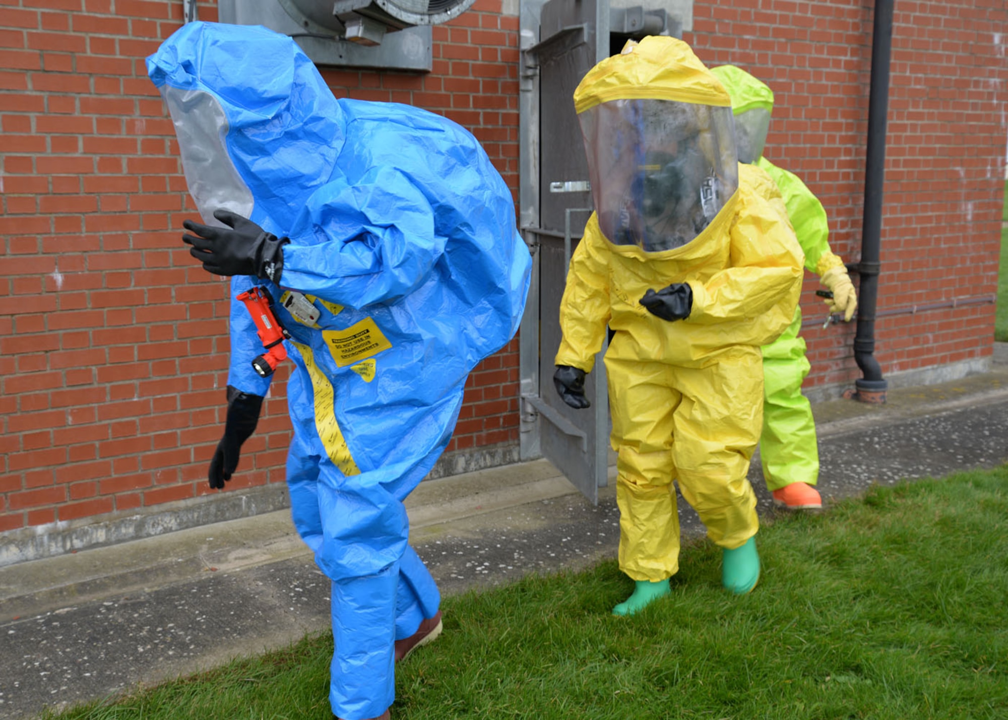 U.S. Air Force Staff Sgt. Jeffrey Gomez, left, 48th Aerospace Medicine Squadron Bioenvironmental Engineering flight technician, U.S. Air Force Senior Airman Breanna Faulkner, center, 100th Civil Engineer Squadron Emergency Management journeyman, and U.S. Air Force Tech. Sgt. Emmanuel Oloyede, 100th CES Emergency Management craftsman, exit the scene after completing their first entry into an unknown hazardous environment during a joint training exercise Feb. 10, 2016, on RAF Mildenhall, England. After the entry, responders must be thoroughly decontaminated with mass amounts of water to ensure they do not bring any contamination out of the scene. (U.S. Air Force photo by Karen Abeyasekere/Released)