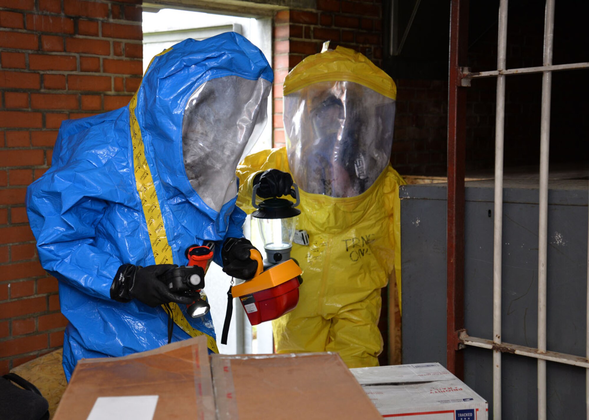U.S. Air Force Staff Sgt. Jeffrey Gomez, left, 48th Aerospace Medicine Squadron Bioenvironmental Engineering technician, and U.S. Air Force Senior Airman Breanna Faulkner, 100th Civil Engineer Squadron Emergency Management journeyman, don fully encapsulated Level-A protective suits and practice using radiological and chemical agent detection equipment to identify suspected hazardous material Feb. 10, 2016, on RAF Mildenhall, England. Responders from the 100th CES Fire Department and Emergency Management flight, 48th CES Emergency Management flight, and 48th AMDS Bioenvironmental Engineering flight joined forces to train on responding to a suspicious package containing hazardous materials. (U.S. Air Force photo by Karen Abeyasekere/Released)