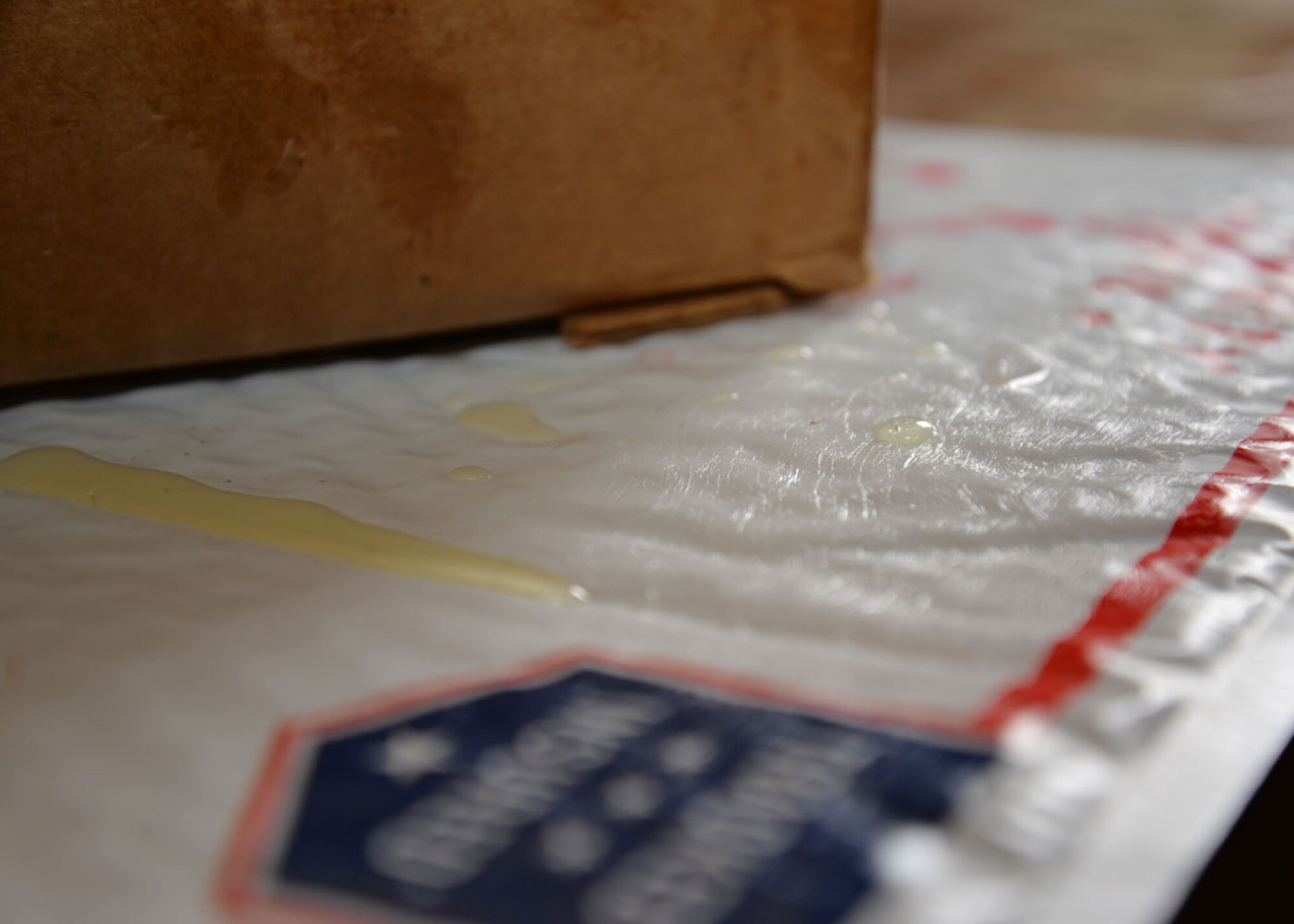A mailing envelope covered in a simulated unknown substance which has leaked from a box awaits testing for possible hazardous chemicals during a training exercise Feb. 10, 2016, on RAF Mildenhall, England. Responders from the 100th Civil Engineer Squadron Fire Department, 100th CES Emergency Management flight, 48th CES Emergency Management flight, and 48th Aerospace Medicine Squadron Bioenvironmental Engineering flight joined forces to train on responding to a suspicious package containing hazardous materials. (U.S. Air Force photo by Karen Abeyasekere/Released)