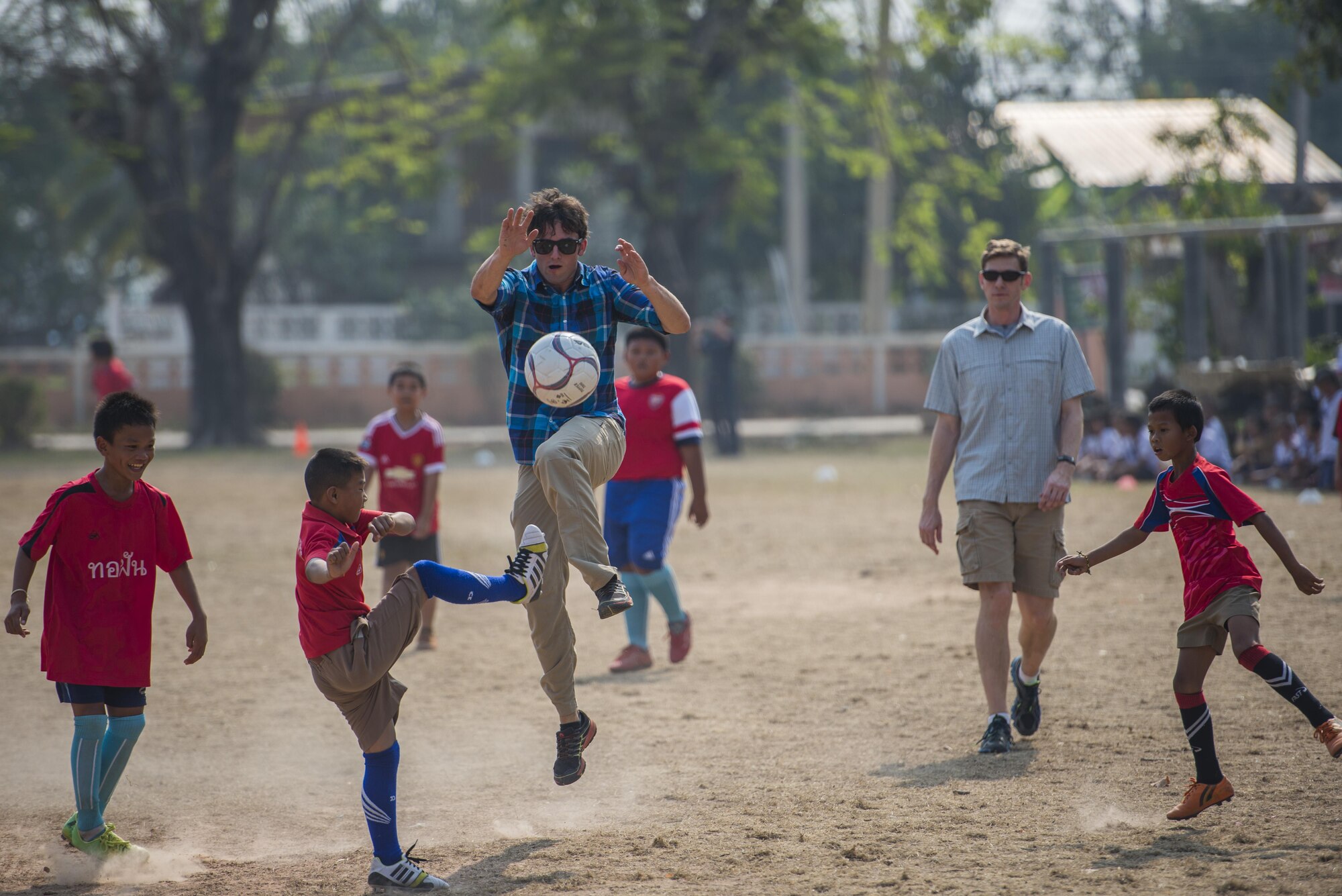 A member of the 320th Special Tactics Squadron plays soccer with kids from Nong-wha Nong-Yai school during a community relations event at Cobra Gold 16, Nam Phong, Thailand, Feb. 15, 2016. Cobra Gold 16 increases cooperation, interoperability and collaboration among partner nations in order to achieve effective solutions to common challenges. (U.S. Air Force photo by Senior Airman Stephen G. Eigel)