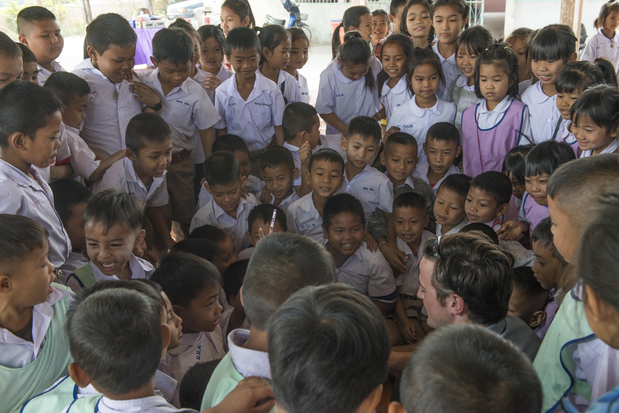 A member of the 320th Special Tactics Squadron takes photos with kids from Nong-wha Nong-Yai school during a community relations event at Cobra Gold 16, Nam Phong, Thailand, Feb. 15, 2016. Members of the 320th STS spend the day with students playing soccer and other games with the children. (U.S. Air Force photo by Senior Airman Stephen G. Eigel)