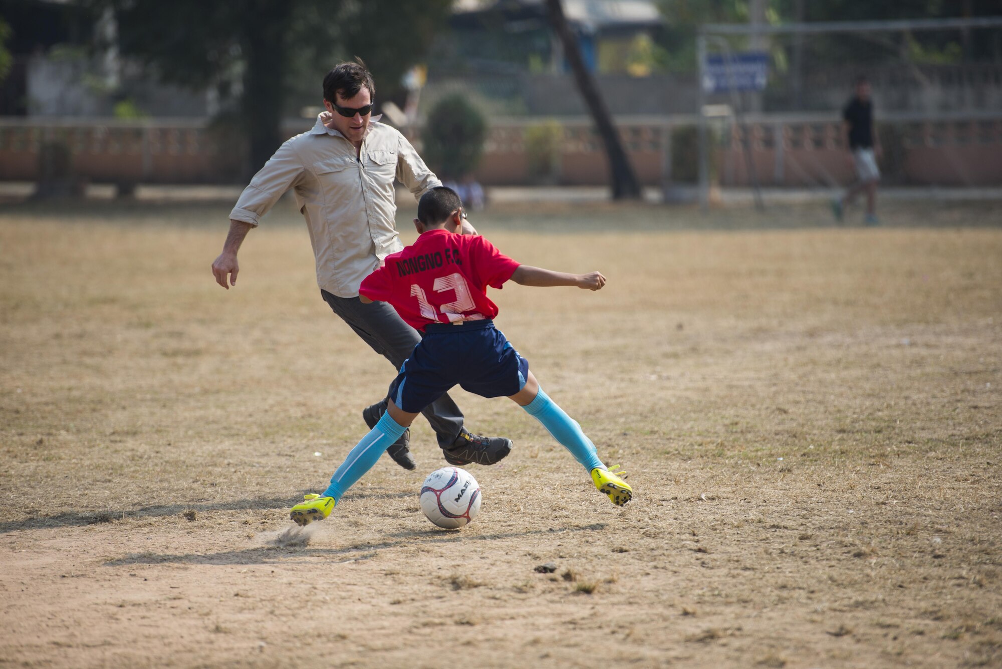 A member of the 320th Special Tactics Squadron plays soccer with kids from Nong-wha Nong-Yai school during a community relations event at Cobra Gold 16, Nam Phong, Thailand, Feb. 15, 2016. Members of the 320th STS spend the day with students playing soccer and ended up losing 4 to 1 at the end of two halves. (U.S. Air Force photo by Senior Airman Stephen G. Eigel)