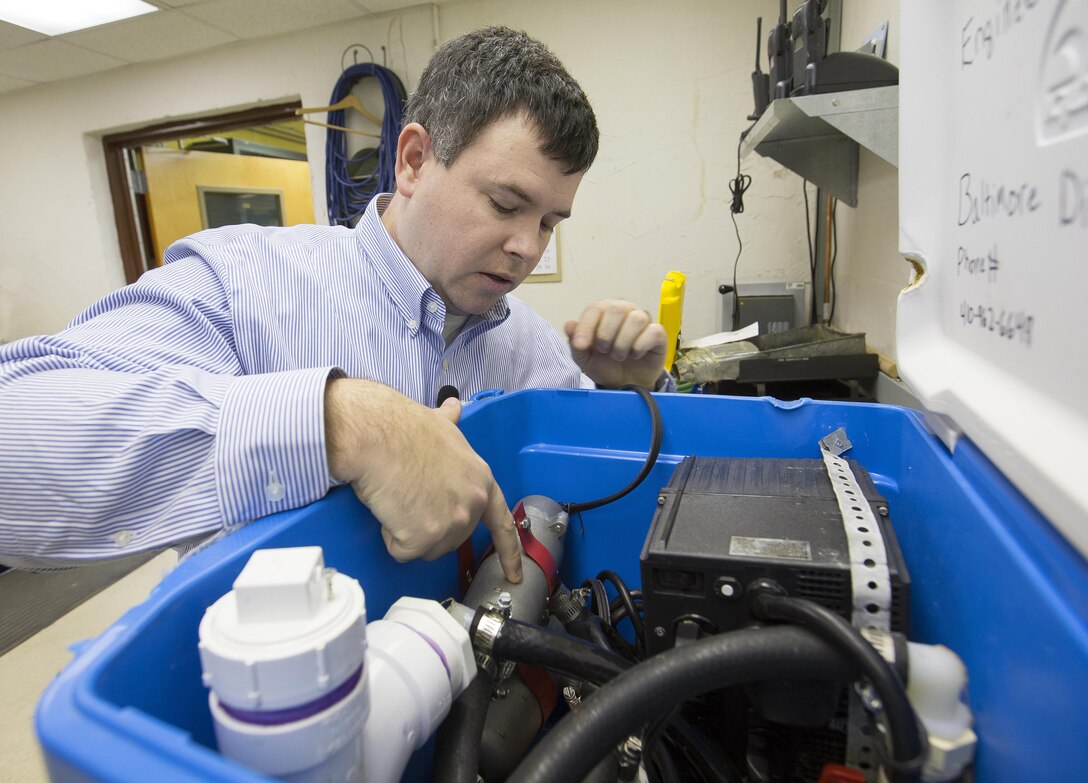 Geologist Ethan Weikel points to the miniature heater in the ground-source heat pump system he developed. Weikel's system, housed in a portable ice chest, gives engineers a more mobile and less costly way to measure the heat transfer capabilities in the earth. His work earned him the 2015 USACE Innovation of the Year award.