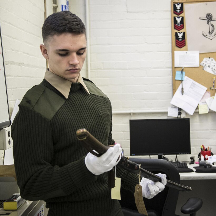 Lance Cpl. Trever Kelly, operations deck crew, Headquarters and Service Company, Marine Barracks Washington, D.C., carefully examines a historical Japanese katana surrendered during World War II, Feb. 26, 2016. The Marines from H&S Co. visited the National Museum of the United States Navy at the Washington Navy Yard, to learn more about the history and traditions of their sister service. (Official Marine Corps photo by Cpl. Chi Nguyen/Released)