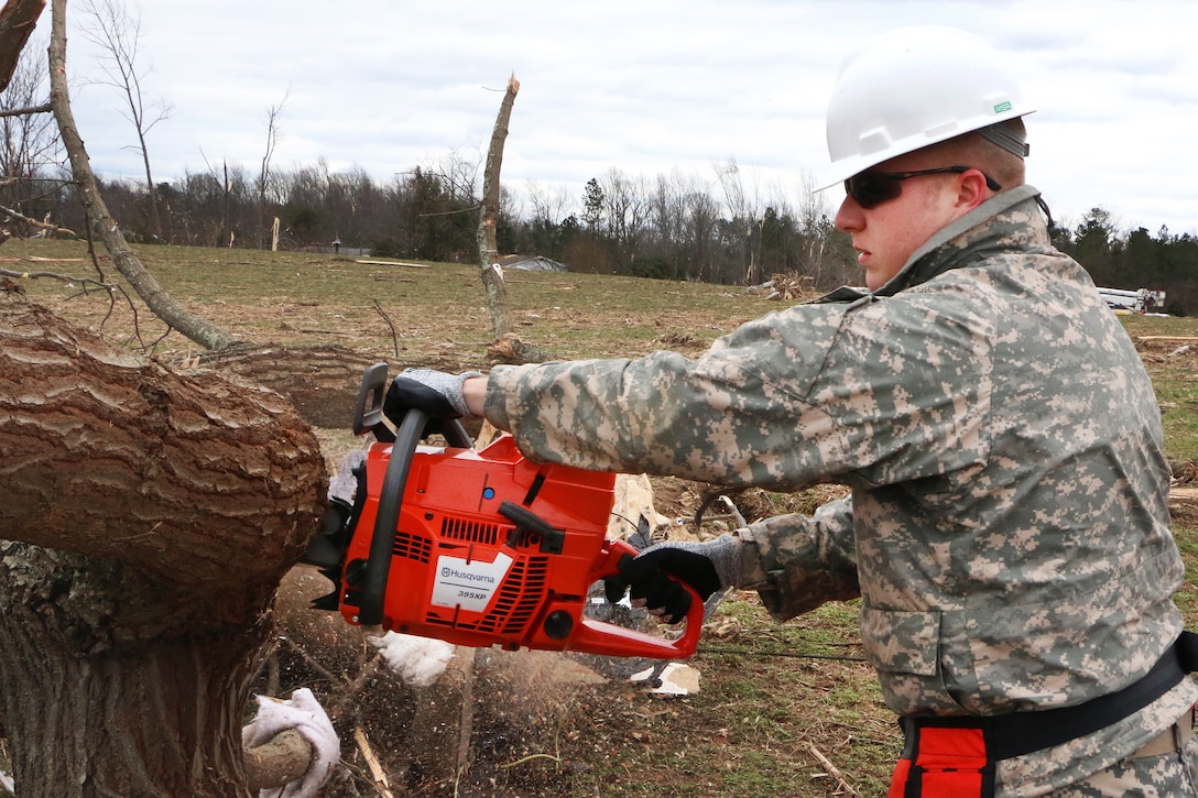 A soldier saws through tree branches and clears debris to open a blocked road in Essex County, Va., Feb. 25, 2016. The soldier is assigned to the Virginia National Guard’s 180th Engineer Company, 276th Engineer Battalion, 91st Troop Command. More than 40 guardsmen are on state active duty assisting with cleanup operations following storms across Virginia. Virginia National Guard photo by Alfred Puryear