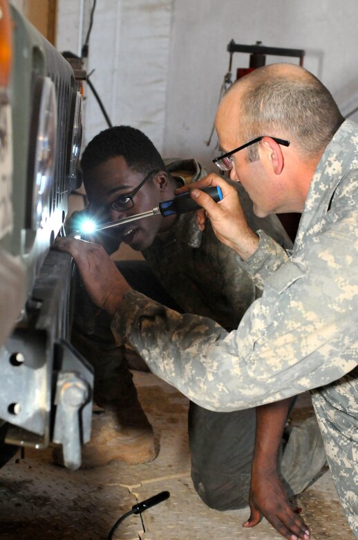 Sgt. Jesse Bankston (front), a wheeled vehicle mechanic for 103rd Quartermaster Company and a Houston native, and Pfc. Da Quan Coker, a wheeled vehicle mechanic with the 542nd SMC and Philadelphia native, reassemble a Humvee hood after successfully repairing a water pump Feb. 18 at Fort Polk, La. The maintenance bay has been home to mechanics from several different units and components during the Joint Readiness Training Center's rotation 16-04 operation. The Soldiers have come together during the exercise to provide maintenance support for the 4th Brigade Combat Team (Airborne). (U.S. Army Photo by Sgt. Aaron Ellerman 204th Public Affairs Detachment/Released)
