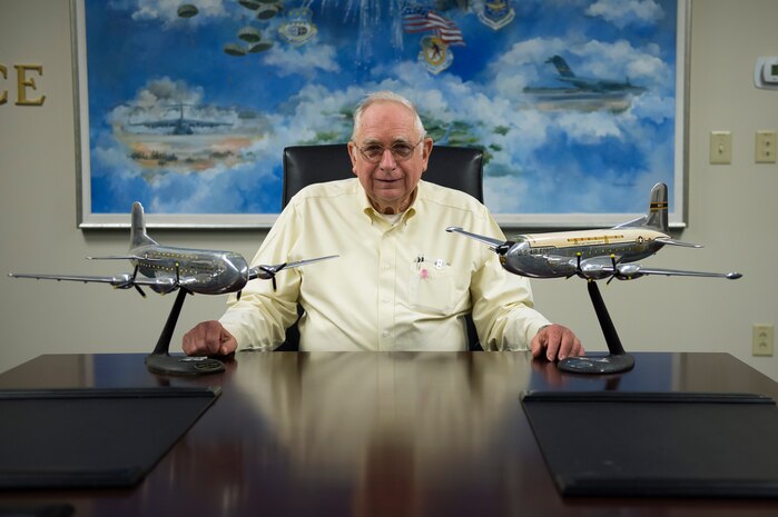 Frank Metzger, a Wing Plans program analyst with the 437th Airlift Wing, smiles behind two C-124 Globemaster II model aircraft, Feb. 24, 2016, at Joint Base Charleston, S.C. Metzger, who is retiring after 54 years of combined federal service, served in the military as a navigator for 24 years and his first assignment was with the 1608th Air Transport Wing at Charleston Air Force Base, where he flew in C-124s. The C-124, nicknamed “Old Shaky,” is an unpressurized cargo plane that had to be flown low and in the weather. Metzger flew in a C-124 over the North Atlantic Ocean in the winter.(U.S. Air Force photo/Staff Sgt. Jared Trimarchi)