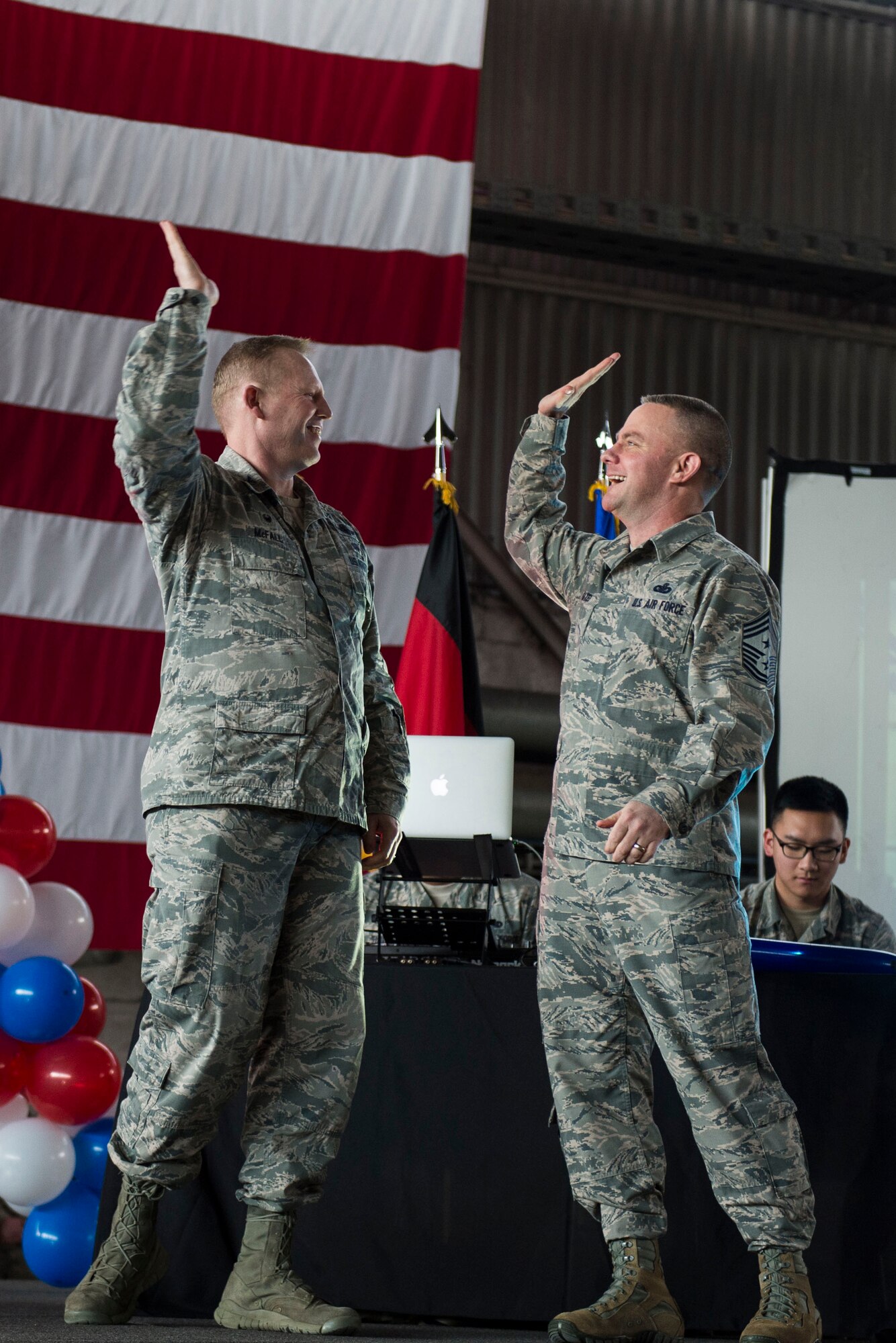 U.S. Air Force Col. Joe McFall, 52nd Fighter Wing commander, left, celebrates with U.S. Air Force Chief Master Sgt. Brian Gates, 52nd FW command chief, during the Year in Review Pep Rally in Hangar 1 at Spangdahlem Air Base, Germany, Feb. 25, 2016. McFall and Gates handed out jerseys to the 52nd Fighter Wing 2015 annual awards nominees to recognize their accomplishments. (U.S. Air Force photo by Airman 1st Class Luke Kitterman/Released)