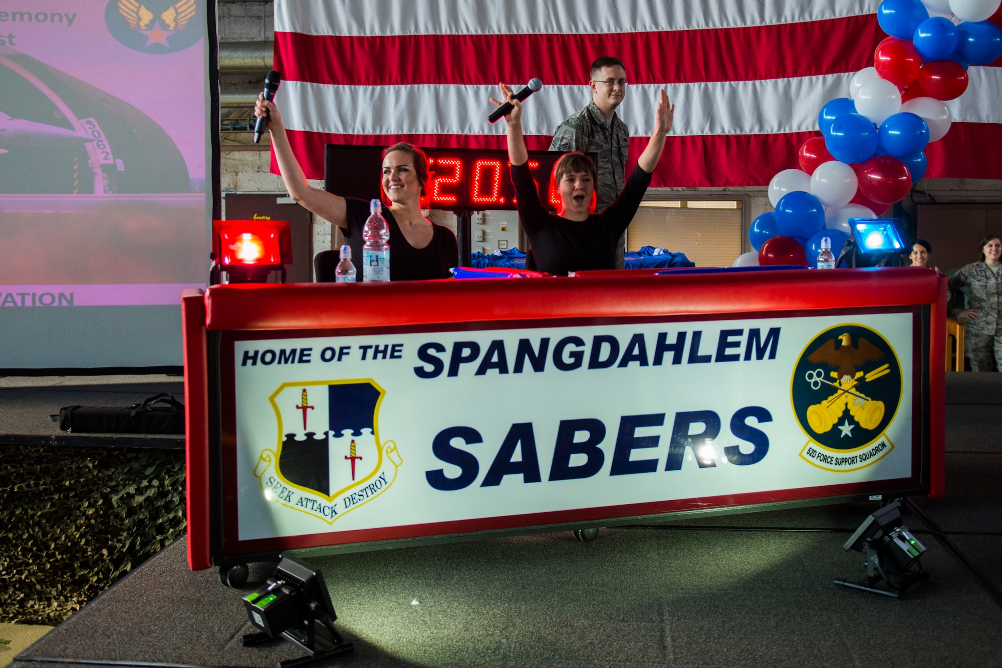 U.S. Air Force Airman Taylor Bridges, a 52nd Force Support Squadron military personnel section member, left, and U.S. Air Force 1st Lt. Katelin Shipp, 52nd FSS MPS chief, take their seats on stage at the beginning of the Year in Review Pep Rally in Hangar 1 at Spangdahlem Air Base, Germany, Feb. 25, 2016. Bridges and Shipp hosted the event and introduced the 52nd Fighter Wing 2015 annual awards nominees. (U.S. Air Force photo by Airman 1st Class Luke Kitterman/Released)