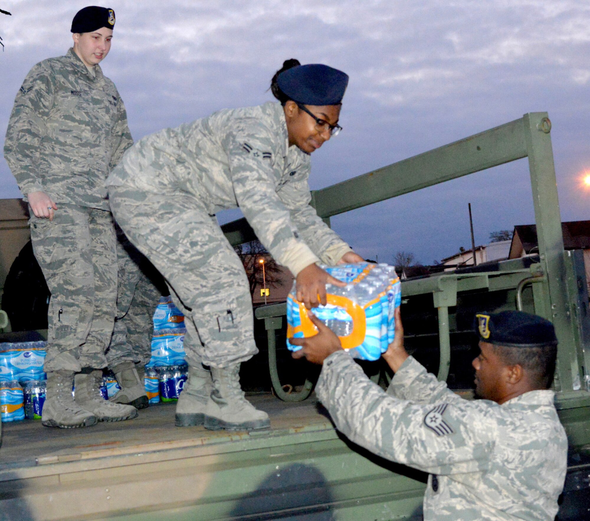 Staff Sgt. Kendall Iverson, 78th Security Forces Squadron flight chief, hands a case of water to entry controllers Airmen First Class Shaquan Roberts and Aleia Moss, Feb 25, 2016. The unit collected five tons of bottled water to help Flint residents with their water crisis. (U.S. Air Force photo by Ray Crayton)