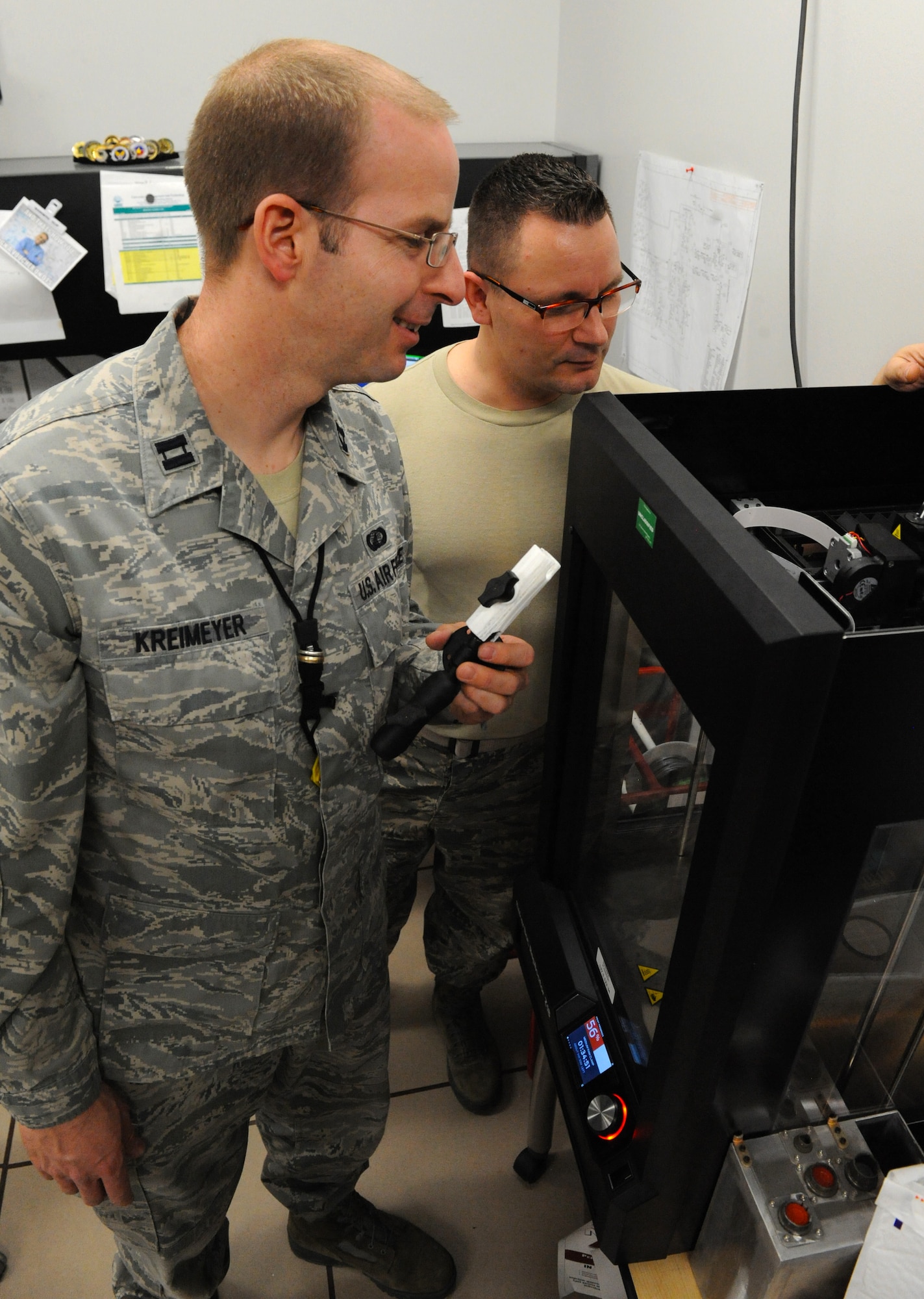 U.S. Air Force Capt. Wayne Kreimeyer, the 509th Maintenance Group (MXG) Research and Engineering (RE) flight commander, right, reviews the progress of a 3-D print with Master Sgt. James Gargano, an RE technician with the 509th MXG, at Whiteman Air Force Base, Mo., Feb. 18, 2016. The 3-D model is used for “form-fit function.” The form-fit function method prints an object for specification prior to sending to the metals technology shop for fabrication. (U.S. Air Force photo by Tech. Sgt. Miguel Lara III)