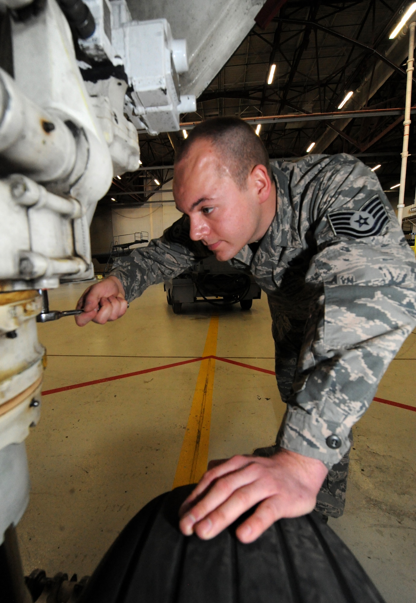 U.S. Air Force Tech Sgt. Aaron Bradley, a 393d Aircraft Maintenance Unit specialist section chief, uses a socket wrench to adjust the front landing gear of a B-2 Spirit at Whiteman Air Force Base, Mo., Feb. 18, 2016. When needed, Bradley wears a headset to communicate with a second member in the cockpit—who applies hydraulic pressure. This method allows the crew to adjust the steering of the front landing gear without actually turning the wheel, which prevents wear on the tires. (U.S. Air Force photo by Tech. Sgt. Miguel Lara III)
