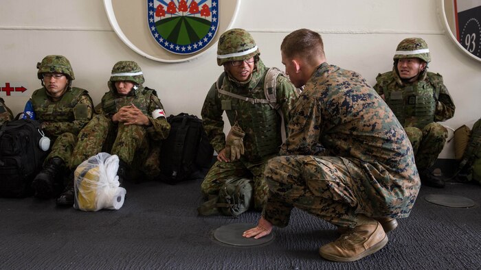 AT SEA - Lance Cpl. Aric Gall, an interpreter attached to the 11th Marine Expeditonary Unit, speaks to a soldier with Western Army, Japan Ground Self-Defense Force, aboard the USS Somerset (LPD 25), Feb. 21, 2016, prior to their debarkation to San Clemente Island in preparation for the supported arms coordination center exercise(SACCEX) portion of Exercise Iron Fist 2016. Iron Fist is an annual, bilateral amphibious training exercise designed to improve USMC and JGSDF’s ability to plan, communicate and conduct combined amphibious operations at the platoon, company and battalion levels.