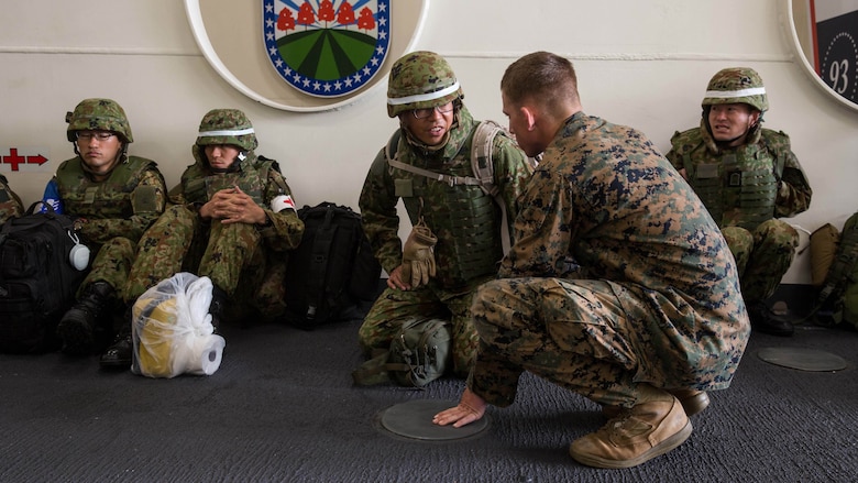 AT SEA - Lance Cpl. Aric Gall, an interpreter attached to the 11th Marine Expeditonary Unit, speaks to a soldier with Western Army, Japan Ground Self-Defense Force, aboard the USS Somerset (LPD 25), Feb. 21, 2016, prior to their debarkation to San Clemente Island in preparation for the supported arms coordination center exercise(SACCEX) portion of Exercise Iron Fist 2016. Iron Fist is an annual, bilateral amphibious training exercise designed to improve USMC and JGSDF’s ability to plan, communicate and conduct combined amphibious operations at the platoon, company and battalion levels.