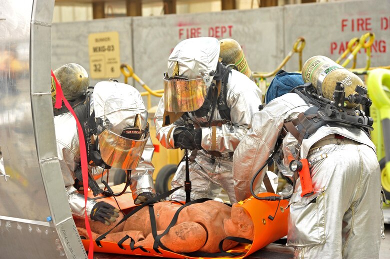 Firefighters from the 380th Expeditionary Civil Engineer Squadron secure and package a patient during a demonstration of a new aircraft trainer at an undisclosed location in Southwest Asia, Feb. 19. The fire department search and rescue aircraft trainer resembles the fuselage of a C-130 frame and serves as a multi-function trainer for entering and exiting a downed or damaged aircraft, packaging a patient in a confined space and cutting into the frame of an aircraft. (U.S. Air Force photo by Staff Sgt. Kentavist P. Brackin/released)