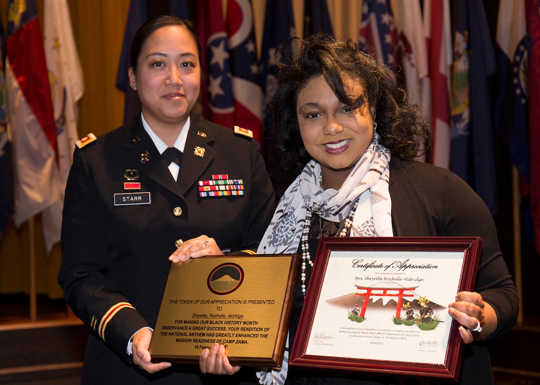 Maj. Nicole Starr, battalion executive officer, assigned to 88th Military Police Battalion, gives Shayetta Rochelle Aldridge a certificate of appreciation and a plaque for her rendition of the US National Anthem during the Camp Zama Black History Month Observance held Feb 18, at the Camp Zama Community Activity Center. (U.S. Army photo by Yuichi Imada)