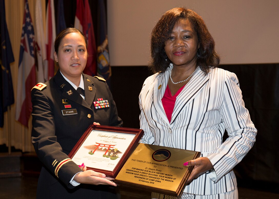 Maj. Nicole Starr, battalion executive officer, assigned to 88th Military Police Battalion, gives guest speaker, Dr. Maggie Rivers, a certificate of appreciation and a plaque during the Camp Zama Black History Month Observance held Feb 18, at the Camp Zama Community Activity Center. (U.S. Army photo by Yuichi Imada)