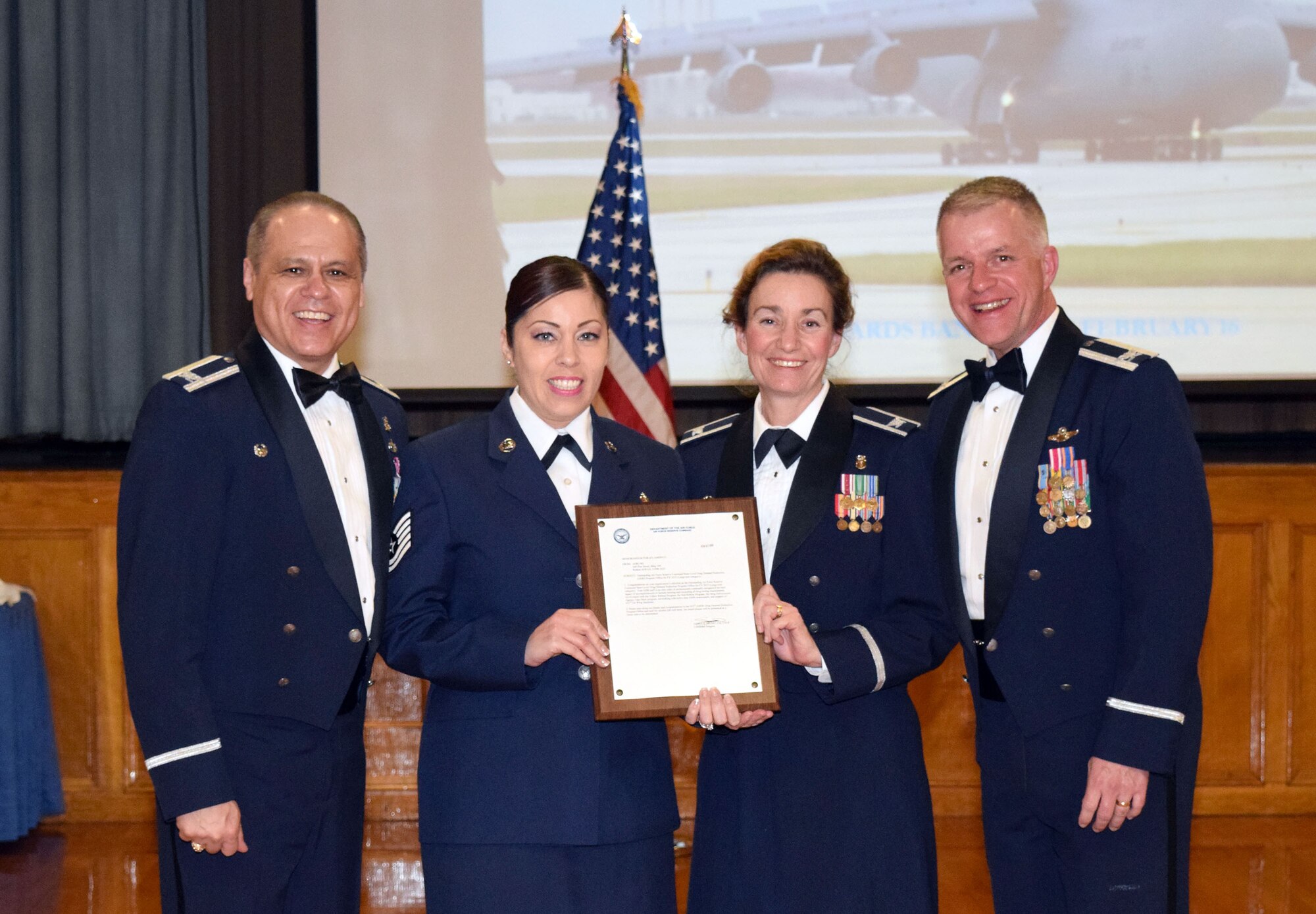 Col. Ernest Vasquez (left), 433rd Medical Group commander, and Col. David Scott (right), 433rd Airlift Wing vice commander, recognize Tech. Sgt. Janice Penuelaz, 433rd Aerospace Medicine Squadron Drug Demand Reduction Program team member, and Col. Julianne Flynn, 433rd AMDS commander, for their role in garnering the Outstanding Air Force Reserve Command Base-Level Drug Demand Reduction Program Office for 2015 (Large-size category) during the 433rd AW Annual Awards Banquet Feb. 27, 2015 at Mitchell Hall, Joint Base San Antonio-Lackland, Texas.  (U.S. Air Force photo by Tech. Sgt. Lindsey Maurice) 