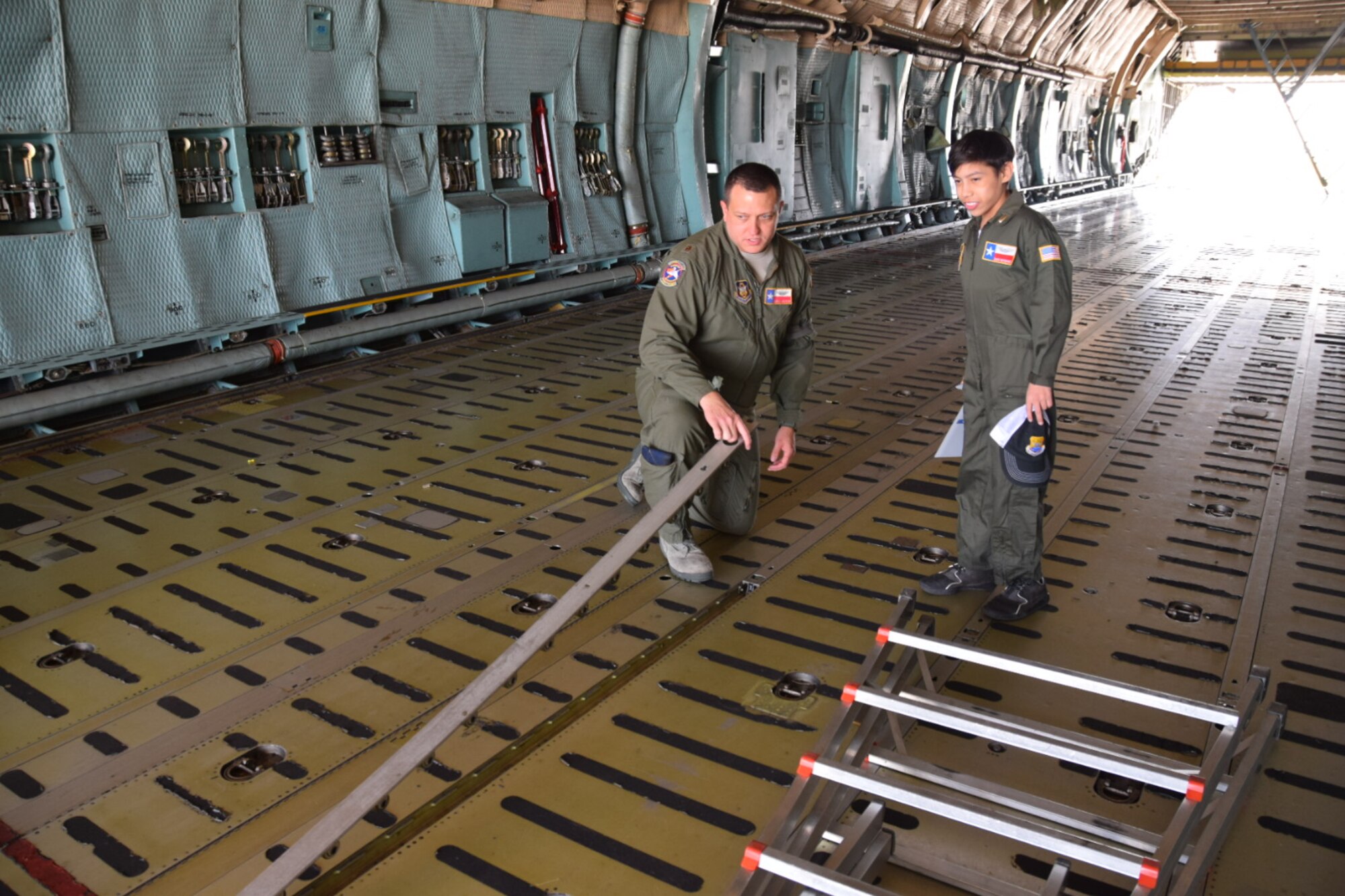 Maj. Chris Melton, a C-5A Galaxy pilot and 68th Aerial Squadron Director of Operations, demonstrates how the floor can be changed to accommodate  to Zach Gutierrez, the 433rd Airlift Wing’s Pilot for a Day.   The goal of the Pilot for a Day program is to provide children, who have serious or chronic conditions, and their families with the opportunity to be a guest of the 433rd Airlift Wing for a day (U.S. Air Force photo by Tech. Sgt. Carlos J. Trevino)