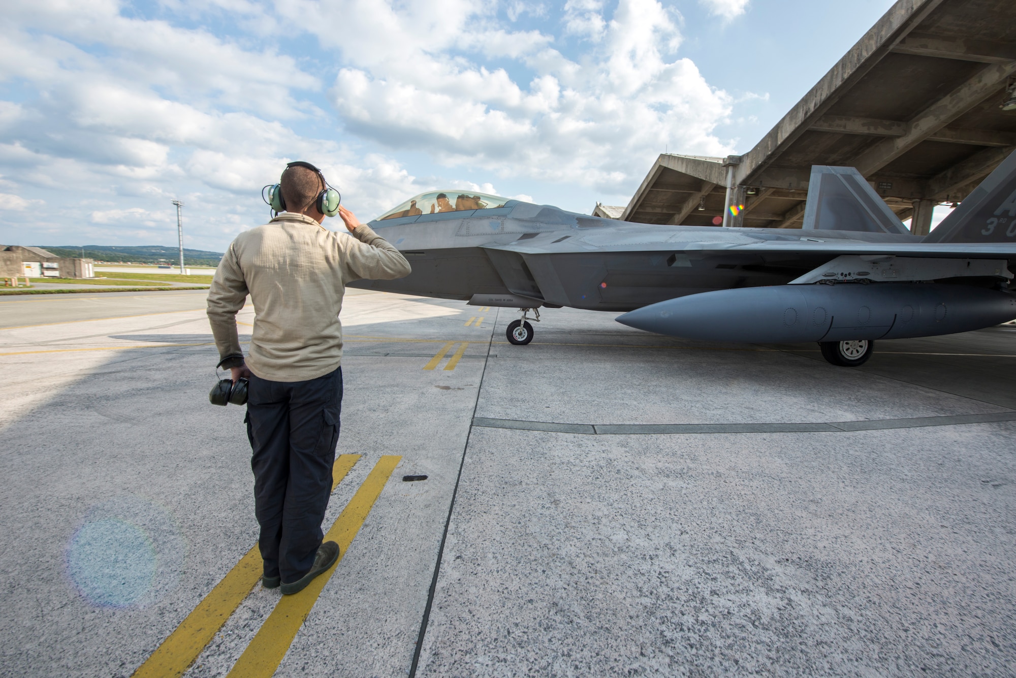 U.S. Air Force Senior Airman Liam Vining, 525th Aircraft Maintenance Unit crew chief, salutes Lt. Col. Brandon Tellez, 525th Fighter Squadron commander, as he taxis an F-22 Raptor for takeoff Feb. 17, 2016, at Kadena Air Base, Japan. The 525th FS from Joint Base Elmendorf Richardson deployed several F-22s to Kadena in January for training exercises in the region. However, while here, the F-22s flew alongside other U.S. and Republic of Korea fighter aircraft over South Korea in response to recent North Korean provocation. (U.S. Air Force photo by Staff Sgt. Maeson L. Elleman)