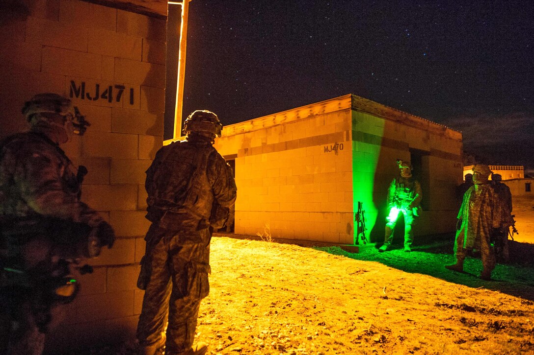 Soldiers take cover behind buildings during a clearance operation exercise in a mock town at the National Training Center, Fort Irwin, Calif., Feb. 18, 2016. The soldiers are assigned to the 1st Cavalry Division’s 3rd Cavalry Regiment. U.S. Army photo by Staff Sgt. Alex Manne