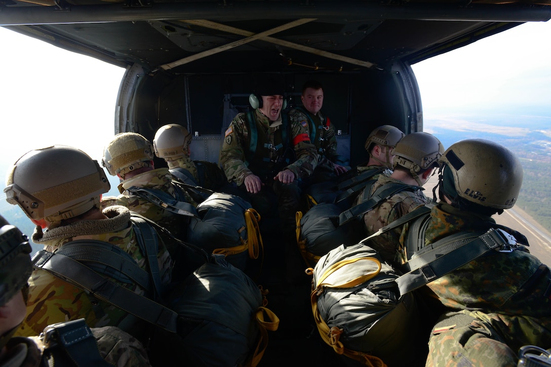 An Army jumpmaster, center, gives commands to U.S. paratroopers, airmen, and German soldiers inside a UH-60 Black Hawk helicopter as part of an airborne exercise over Grafenwoehr Training Area, Germany, Feb. 18, 2016. U.S. Army photo by Pfc. Emily Houdershieldt