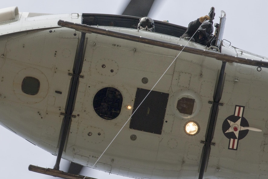 (Left to right) Tech. Sgt. Michael Wright, 459th Airlift Squadron flight engineer, and Tech. Sgt. Christopher Pound, 36th Rescue Squadron special missions aviator evaluator, perform hoist training at Yokota Air Base, Japan, Feb. 22, 2016. The 459th AS recently improved their search and rescue capabilities by outfitting two  Hueys with new rescue hoists. (U.S. Air Force photo by Osakabe Yasuo/Released)