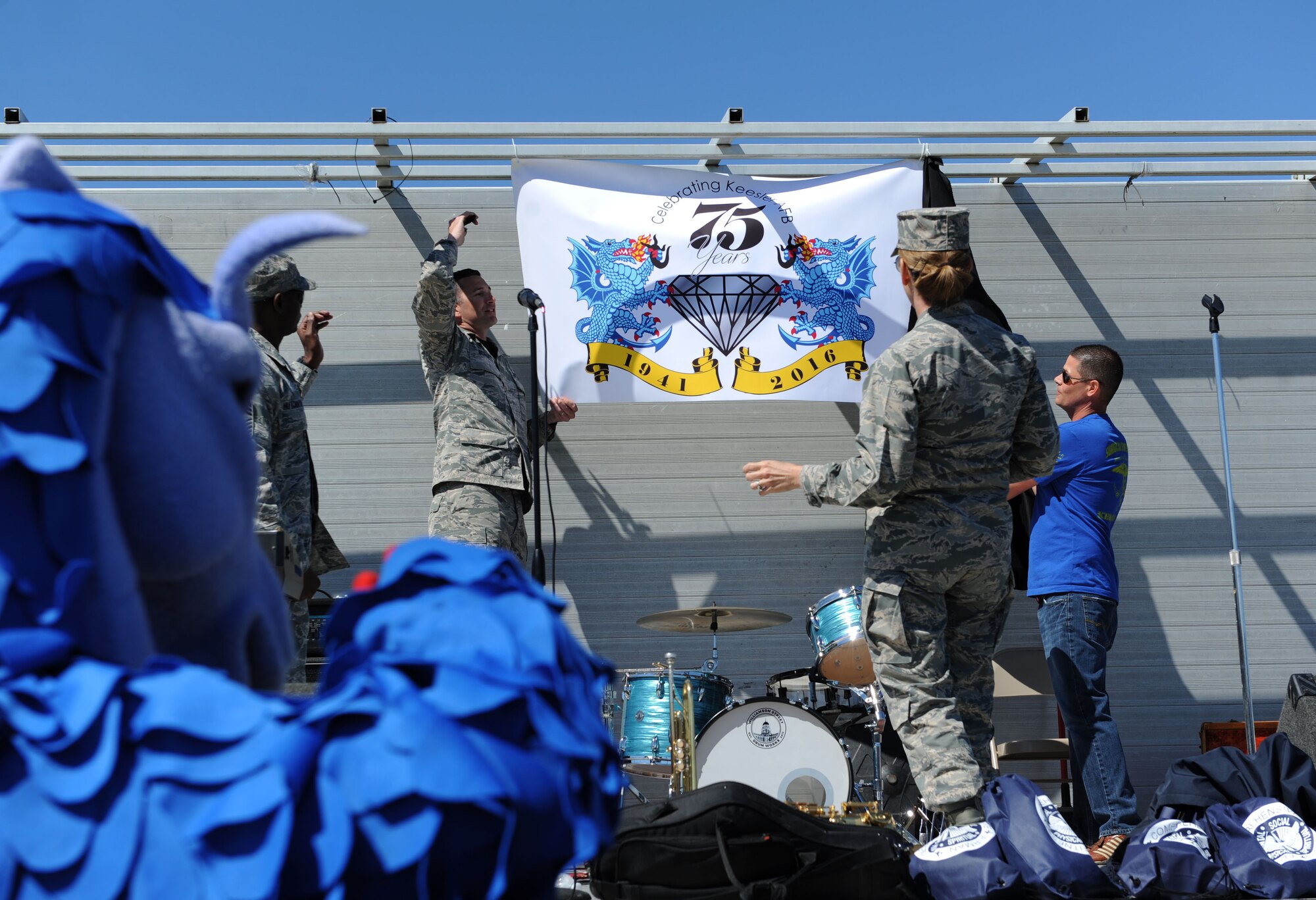 Col. Michele Edmondson, 81st Training Wing commander, stands on stage during the unveiling of Keesler’s 75th Anniversary logo during Dragon Fest, Feb. 26, 2016, Keesler Air Force Base, Miss. Dragon Fest is an organization built to help Airmen grow, mentor and network through shared interests by providing more than 40 groups and private organizations to showcase what they offer. (U.S. Air Force photo by Kemberly Groue)