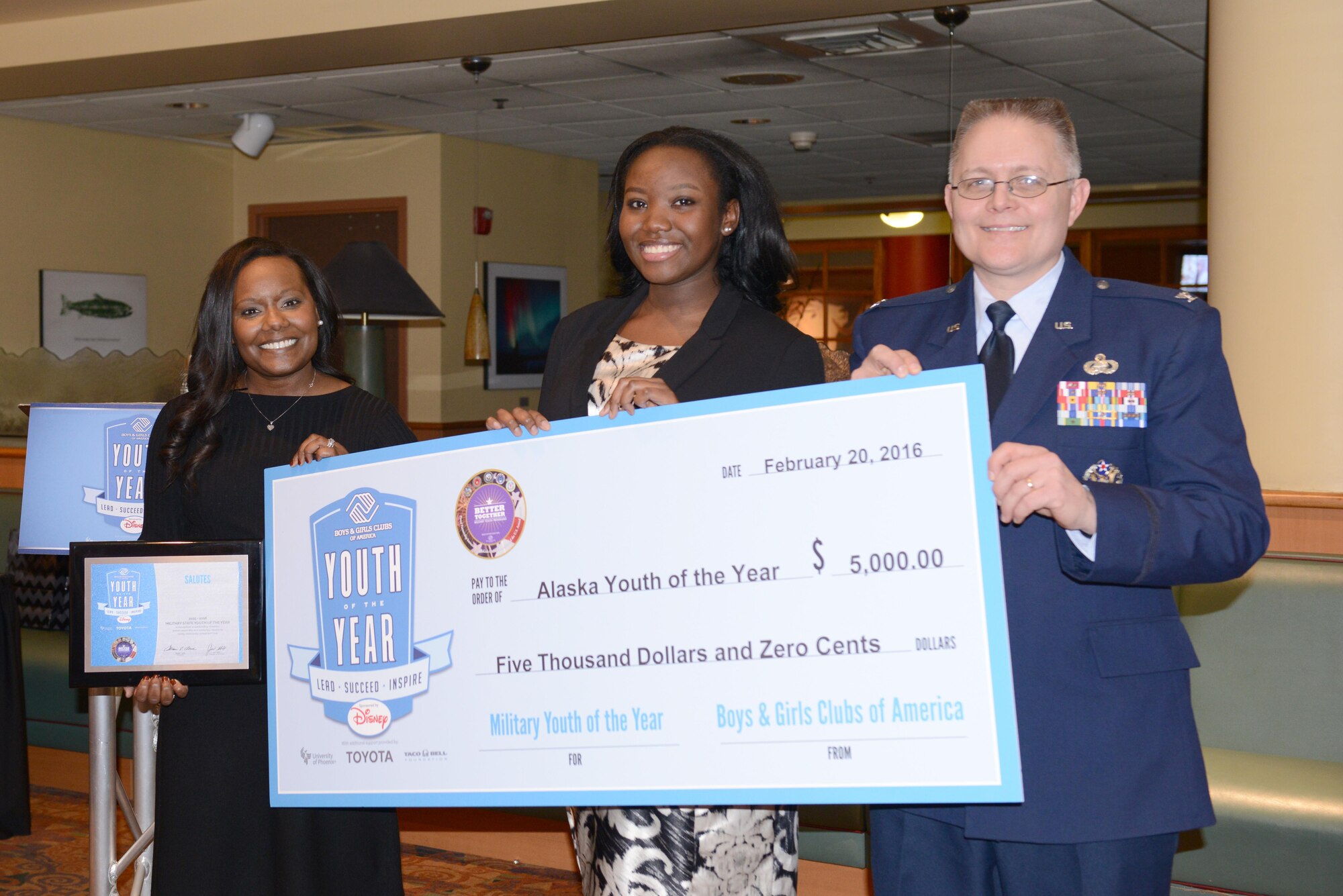 Terrill McFarland, the National Vice-President of Boys & Girls Clubs of America Military Outreach Services, presents a $5,000 scholarship to MiKaila Alexander, a senior at Ben Eielson High School, with Col. Richard Cole, the 354th Mission Support Group commander, during the 2016 Alaska Youth of the Year ceremony at the Westmark Hotel, Feb. 20, 2016, in Fairbanks, Alaska. Alexander won the Military Youth of the Year scholarship for the second year in a row and will compete at the next regional level this summer. (U.S. Air Force photo by Staff Sgt. Ashley Nicole Taylor/Released)
