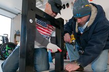 Technical Sgt. Bayardo Rodriguez, 459th Aircraft Maintenance Squadron crew chief (left), and Senior Master Sgt. Karl Schoennagel, 459th AMXS ground equipment flight chief (right), assemble a workbench at U.S. Army Sgt. (ret.) Adam Keys’ home in Annapolis Feb. 27, 2016. Ten members of the 459th AMXS volunteered on behalf of the nonprofit Patriots Honor to unpack, build and install workbenches, power tools and roll-aways in Keys’ garage in an effort to help make dreams come true for wounded warriors. Keys, a triple amputee who has endured more than 130 surgeries due to injuries sustained from an IED explosion in Afghanistan in 2010, intends to use the equipment to pursue his hobby of building small engines and model cars. (U.S. Air Force photo by Staff Sgt. Kat Justen)