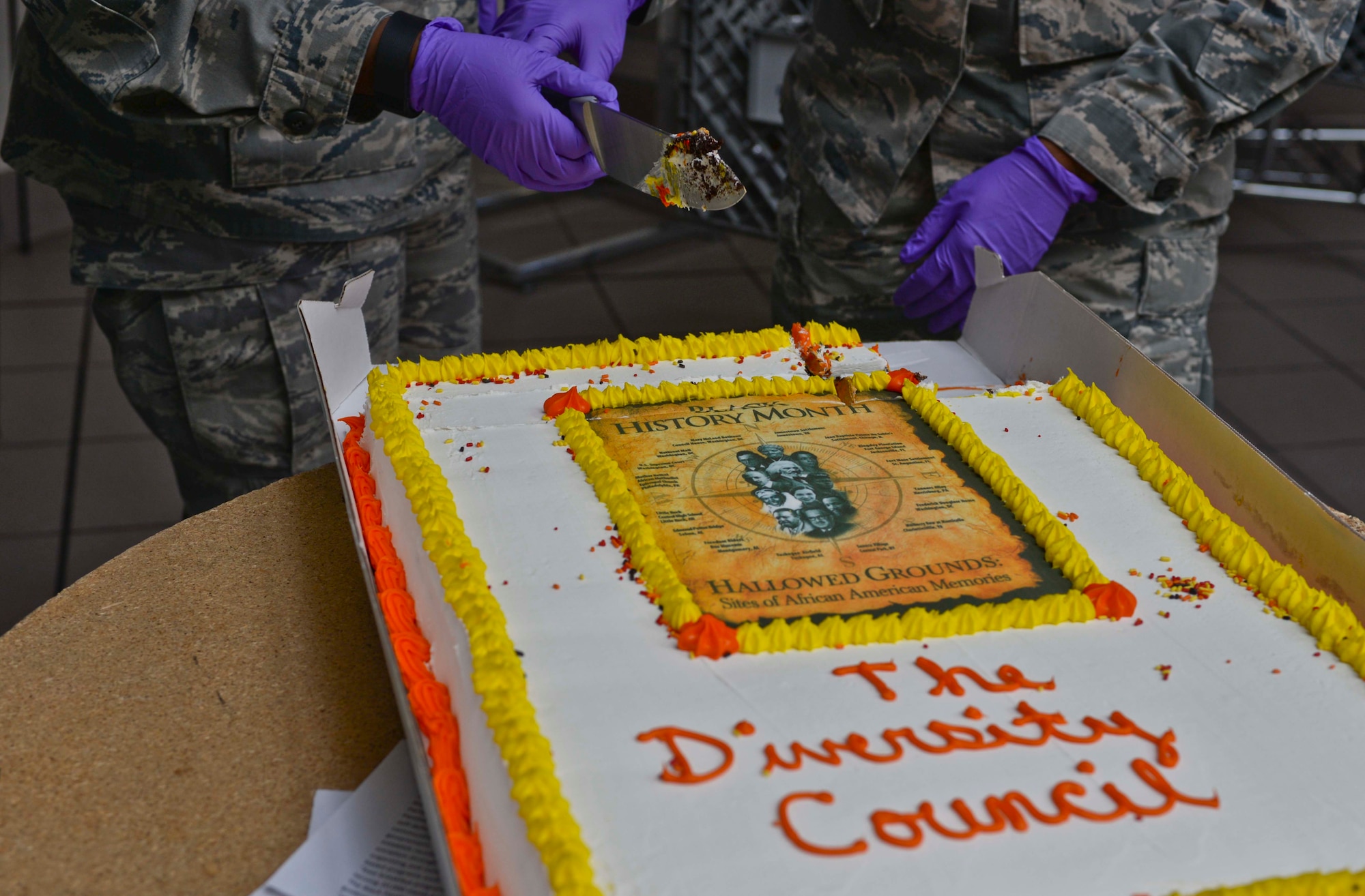 An Airman performs a cake cutting ceremony during a luncheon at Ellsworth Air Force Base, S.D., Feb. 24, 2016. The ceremony honored the accomplishments of African Americans for Black History Month and had more than 80 people in attendance. (U.S. Air Force photo by Airman Sadie Colbert/Released)