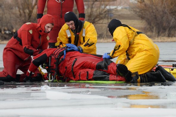 Airmen from the 28th Civil Engineer Squadron Fire Department roll over a simulated victim during ice rescue training at Ellsworth Air Force Base, S.D., Feb. 17, 2016. Obtaining the skills and knowledge to save a life makes ice rescue training a valuable tool. (U.S. Air Force photo by Senior Airman Rebecca Imwalle/Released)