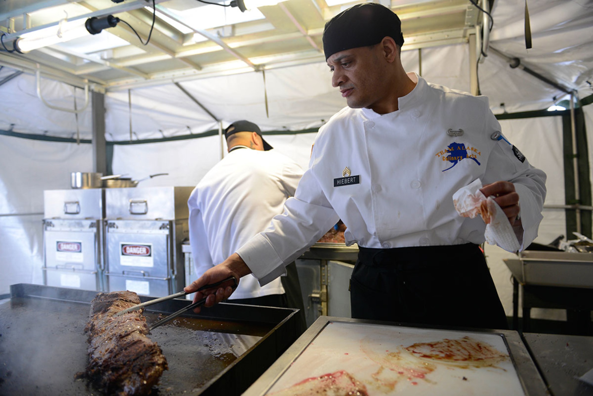 Army Staff Sgt. Patrick Hiebert, E Company, 70th Brigade Engineer Battalion, ‘Team Alaska’ co-captain, removes meat from the grill in a mobile kitchen trailer at Joint Base Elmendorf-Richardson, Feb. 24, 2016.  The 10-person team of Soldiers and Airmen, served up a three-course meal as part of a training event designed to prepare the team for the 41st Annual Military Culinary Arts Competitive Training Event at Fort Lee, VA., March 5 to 10. (U.S. Air Force photo by Airman Valerie Monroy)