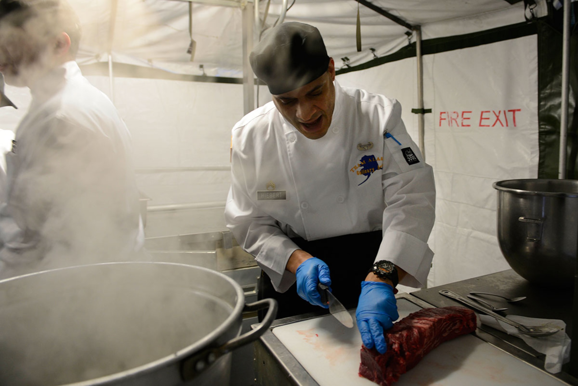 Army Staff Sgt. Patrick Hiebert, E Company, 70th Brigade Engineer Battalion, ‘Team Alaska’ co-captain, cuts meat into steaks in a mobile kitchen trailer at Joint Base Elmendorf-Richardson, Feb. 24, 2016.  The 10-person team of Soldiers and Airmen served up a three-course meal as part of a training event designed to prepare the team for the 41st Annual Military Culinary Arts Competitive Training Event at Fort Lee, VA., March 5 to 10. (U.S. Air Force photo by Airman Valerie Monroy)