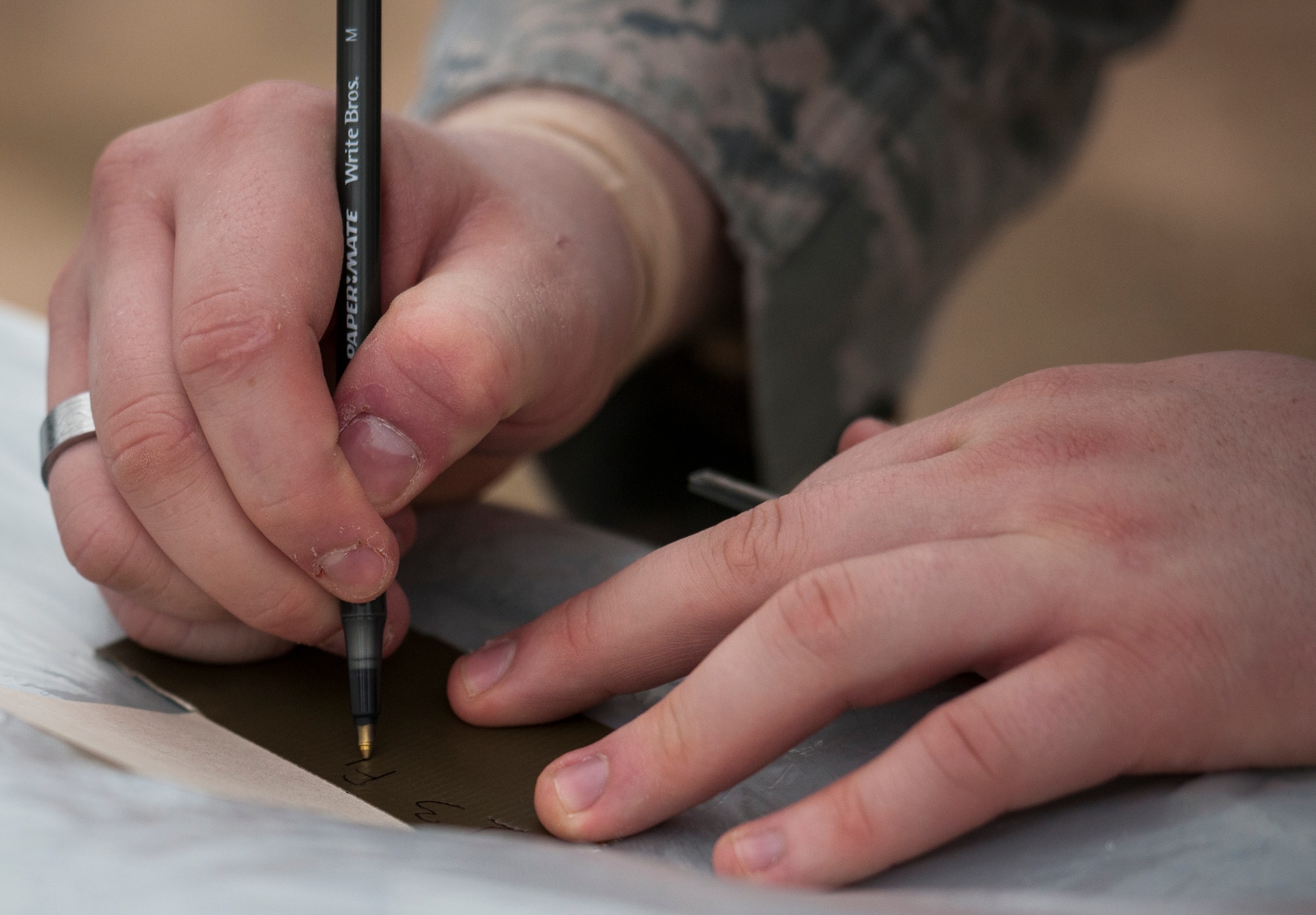 An Airman marks on a piece of tape while securing a piece of equipment during a chemical, biological, radiological, nuclear and explosive training session at Eglin Air Force Base, Fla., Feb. 23.  The course was preparatory training with instructors prior to the live CBRNE exercise.  The Airmen were taught the proper procedures during the training before performing them by themselves during the exercise.  (U.S. Air Force photo/Samuel King Jr.)