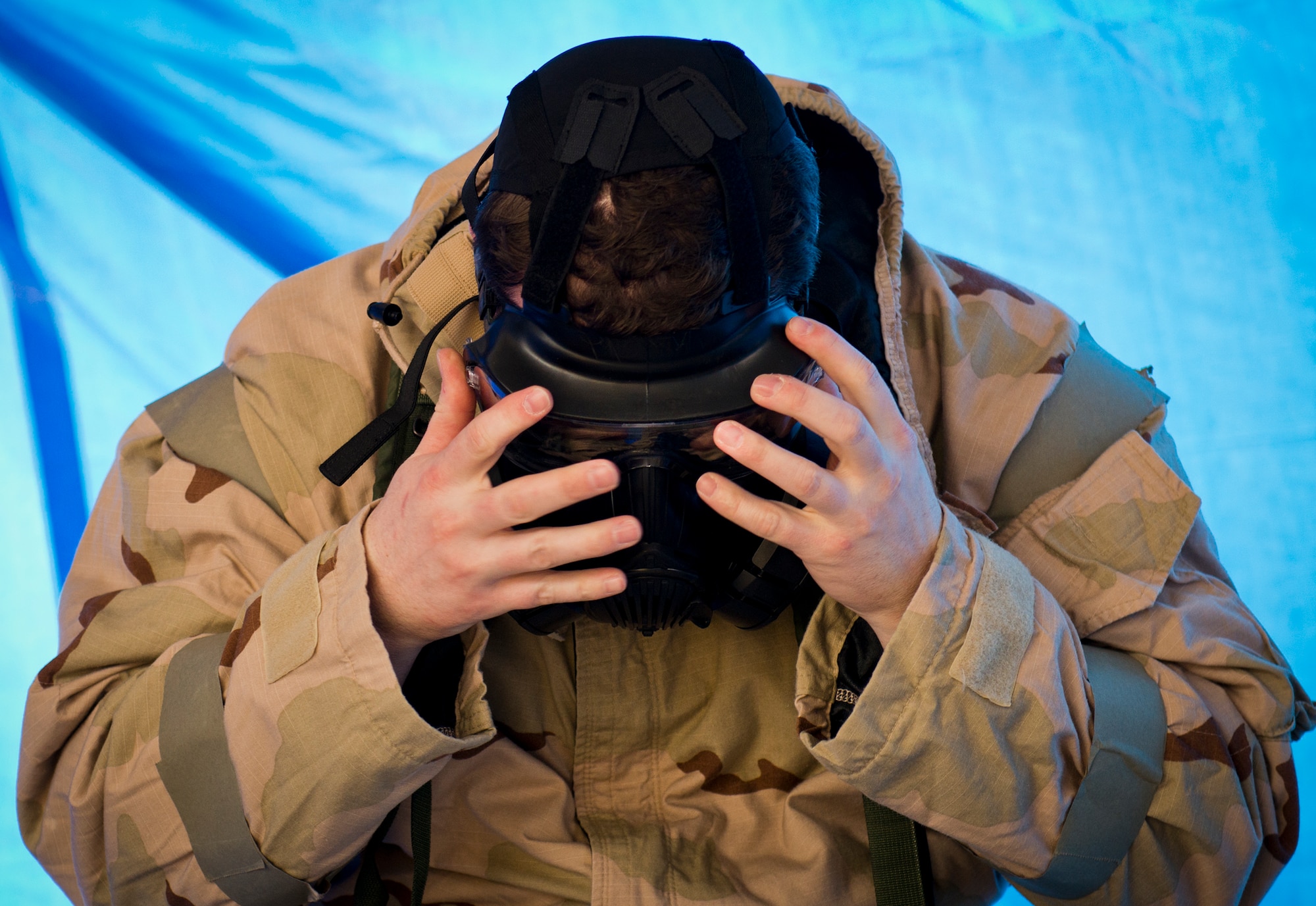 An Airman ensures his M50 gas mask is secure during a chemical, biological, radiological, nuclear and explosive exercise at Eglin Air Force Base, Fla., Feb. 23.  The exercise evaluated the Airmen’s ability to meet wartime and contingency taskings of employing and sustaining the force and the ability to survive and operate.  (U.S. Air Force photo/Samuel King Jr.)