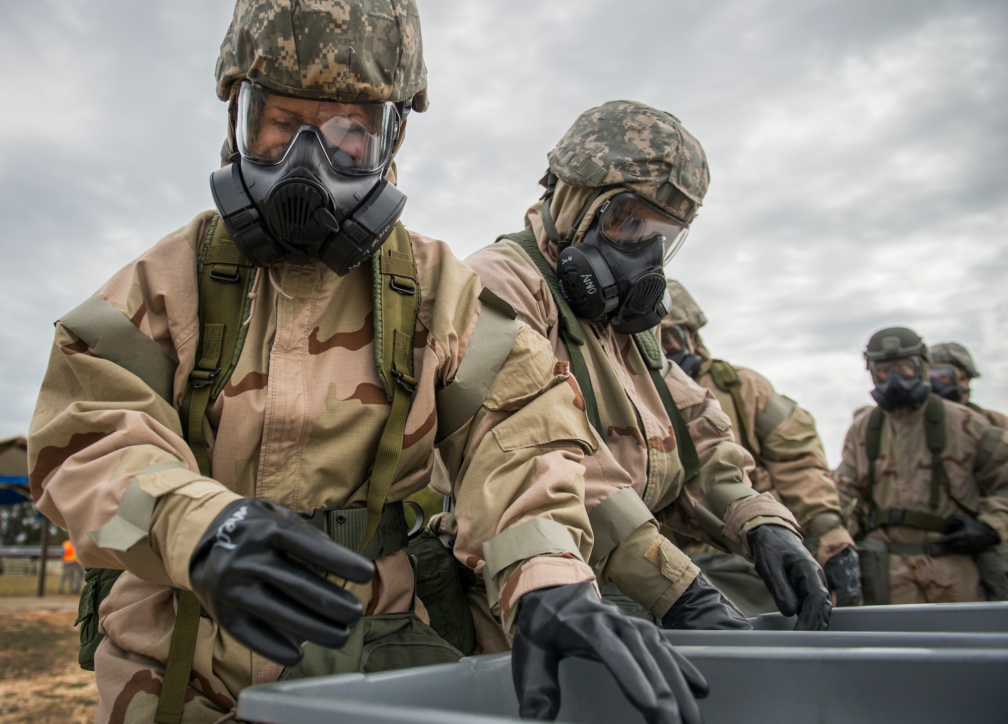 Airmen rinse their protective gloves and boots in a simulated bleach solution during a chemical, biological, radiological, nuclear and explosive training session at Eglin Air Force Base, Fla., Feb. 23.  The course was preparatory training with instructors prior to the live CBRNE exercise.  The Airmen were taught the proper procedures during the training before performing them by themselves during the exercise.  (U.S. Air Force photo/Samuel King Jr.)