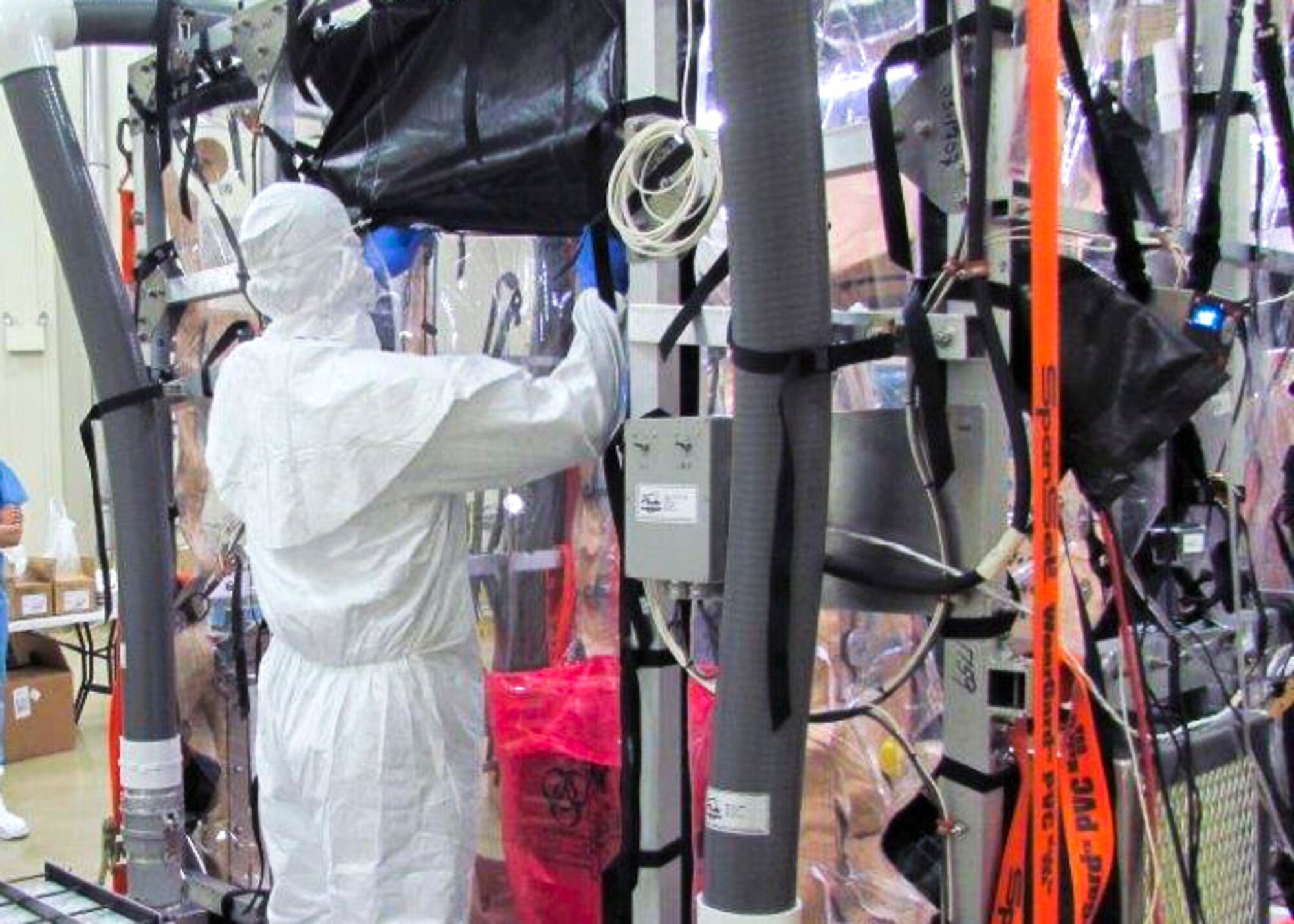 An Airman secures a panel on the Ebola Transport Isolation System at Eglin Air Force Base, Fla. The TIS is an isolation pod that fits within an aircraft allowing for the quarantine of infected patients and containment of the viral particles they release. The suite  provides an area where medical personnel can go inside and through it to care for infected patients without contaminating themselves or the aircraft. (U.S. Air Force/courtesy photo)