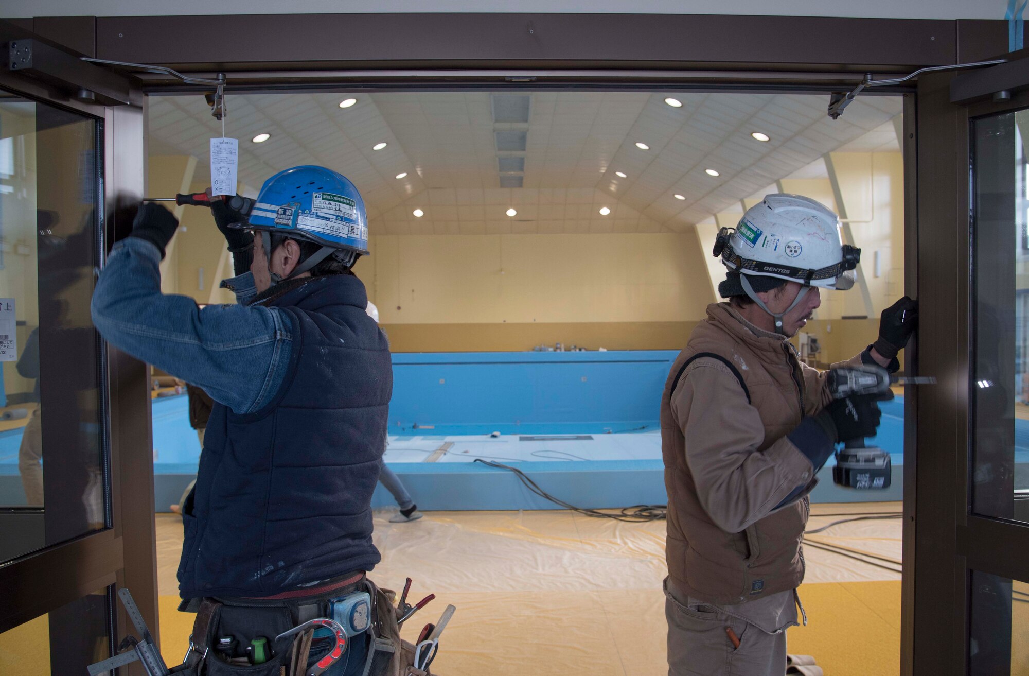 Contractors insert screws into the frame of the Himberg Pool doorway at Misawa Air Base, Japan, Feb. 3, 2016. Although the original construction goal was to replace the pool’s vinyl liner, it was discovered the base plate, facility’s floor, offices, windows and walls also needed renovation. (U.S. Air Force photo by Airman 1st Class Jordyn Fetter) 