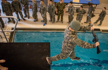 A Clemson University Reserve Officers Training Corps cadet steps off a five-meter diving board - blindfolded - during the Combat Water Survival Test in the Fike Recreation Center Jan. 29, 2015. Cadets had to maintain control of their weapon after hitting the water and return to the side of the pool with it to pass the event. The CWST evaluates each cadet’s stamina in water and their ability to complete three stations while wearing a uniform. Passing the events helps ensure they have the fundamental water survival skills necessary to lead soldiers in a hostile environment where there’s water. (Photo by Ken Scar)