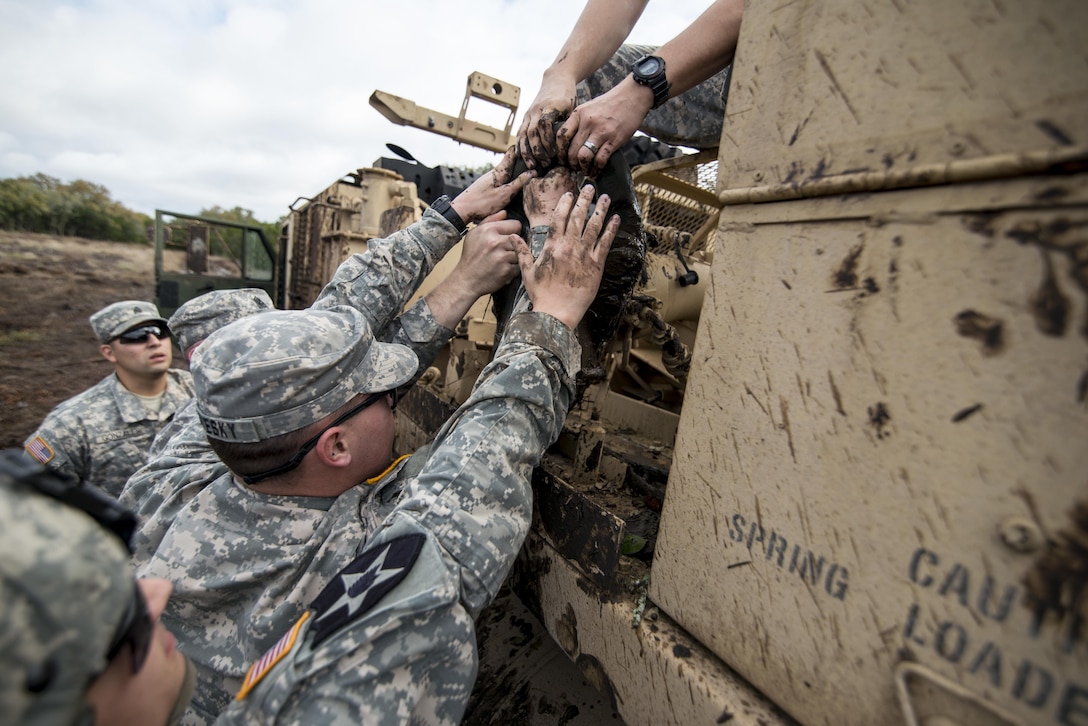 Soldiers from the 277th Engineer Company (Horizontal) and 31st Trailer Transfer Point lift a winch block onto an M984 recovery vehicle during a muddy recovery operation at Camp Bullis, Texas, March 22. (U.S. Army photo by Sgt. 1st Class Michel Sauret)