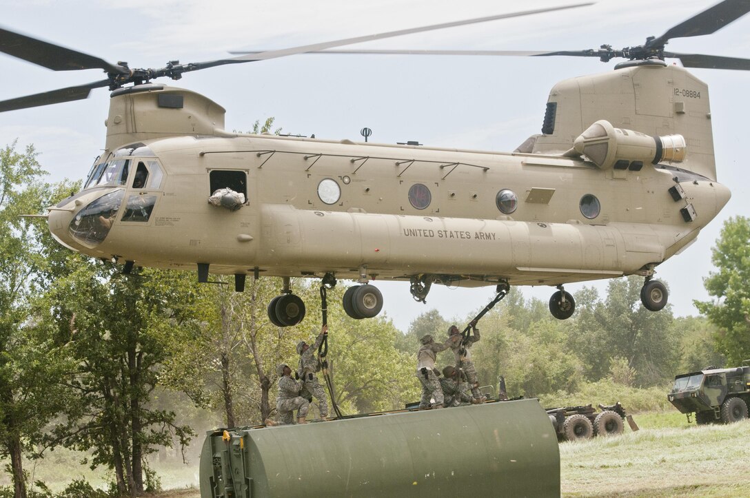 Engineer Soldiers from the 501st, 310th and 341st Engineer Companies brave strong winds to hook up bridge components to Chinook helicopters to be moved to the Arkansas River during River Assault 2015, on July 31, at Fort Chaffee, Ark.