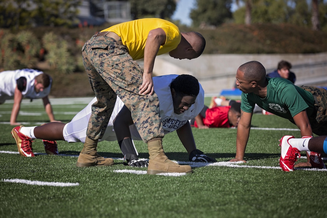 Denzel Okafor, offensive guard from Lewisville High School, Lewisville, Texas, receives motivation from drill instructors during practice at Orange Coast College, Costa Mesa, Calif., Jan. 1, 2016. High School athletes chosen to play in the Semper Fidelis All-American Bowl are well-rounded individuals on and off the field who not only are distinguished athletes, but also have academic achievements and display exemplary moral character. (U.S. Marine Corps photo by Sgt. Rebecca Eller)