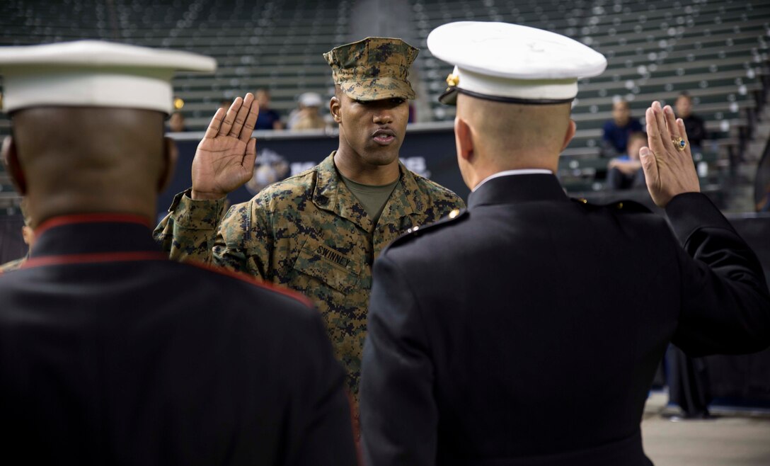 Sgt. Courtney Swinney raises his right hand for his oath of enlistment in front of Brig. Gen. James W. Bierman (right) and Sgt. Maj. James K. Porterfield (left) and during his promotion ceremony to staff sergeant. The ceremony was held prior to the kickoff of the Semper Fidelis All-American Bowl at the Stubhub Center, Carson, Calif., Jan. 3, 2016. Swinney was the Rookie Recruiter of the Year, and was meritoriously promoted to staff sergeant in recognition of his recruiting efforts. Swinney serves at Recruiting Substation Lakewood, Calif., 12th Marine Corps District. Bierman is the Commanding General of Marine Corps Recruit Depot San Diego. Porterfield is the Depot Sgt. Maj. of Marine Corps Recruit Depot San Diego.