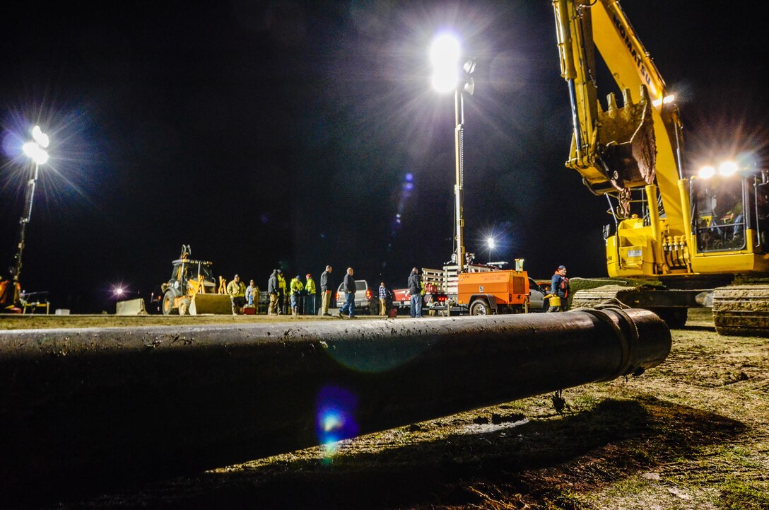 City of Valley Park Public Works officials construct hoses to pump water back over the Valley Park levee on the Meramec River in Missouri, Dec. 31, 2015. Soldiers and airmen assigned to the Missouri National Guard supported the Missouri Department of Transportation in flood relief efforts in south-central Missouri. The focus of the aid is to ensure traffic control, water purification and levee reinforcement in affected areas. Missouri Air National Guard photo by Senior Airman Patrick P. Evenson